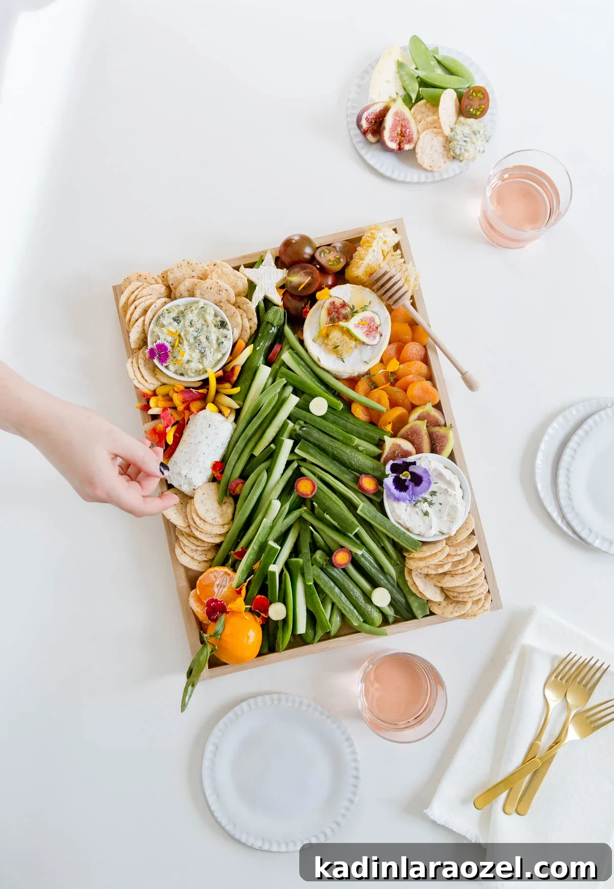 Festive Christmas Charcuterie Board Ideas for Holiday Entertaining 3 Woman's hand reaching for a cracker on a Christmas charcuterie board, shaped like a Christmas tree