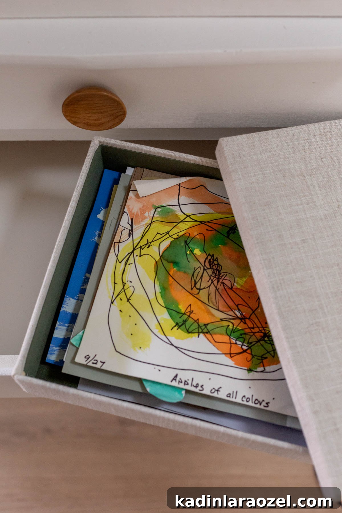 Keepsake organizational box with kids artwork inside, ready to be clipped into a hall closet drawer