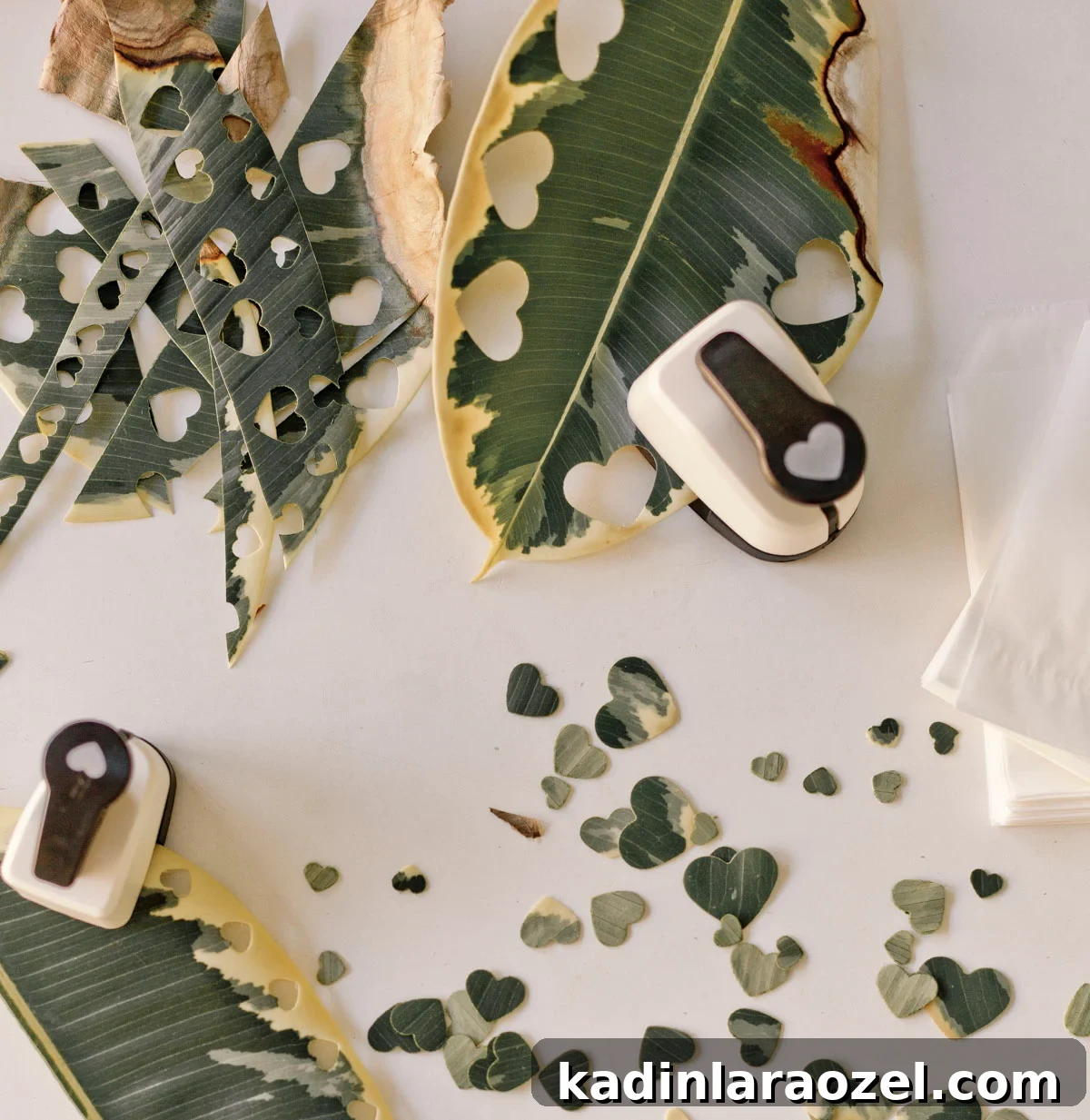 using a heart shaped hole punch to punch holes through leaves to make natural confetti for parties 
