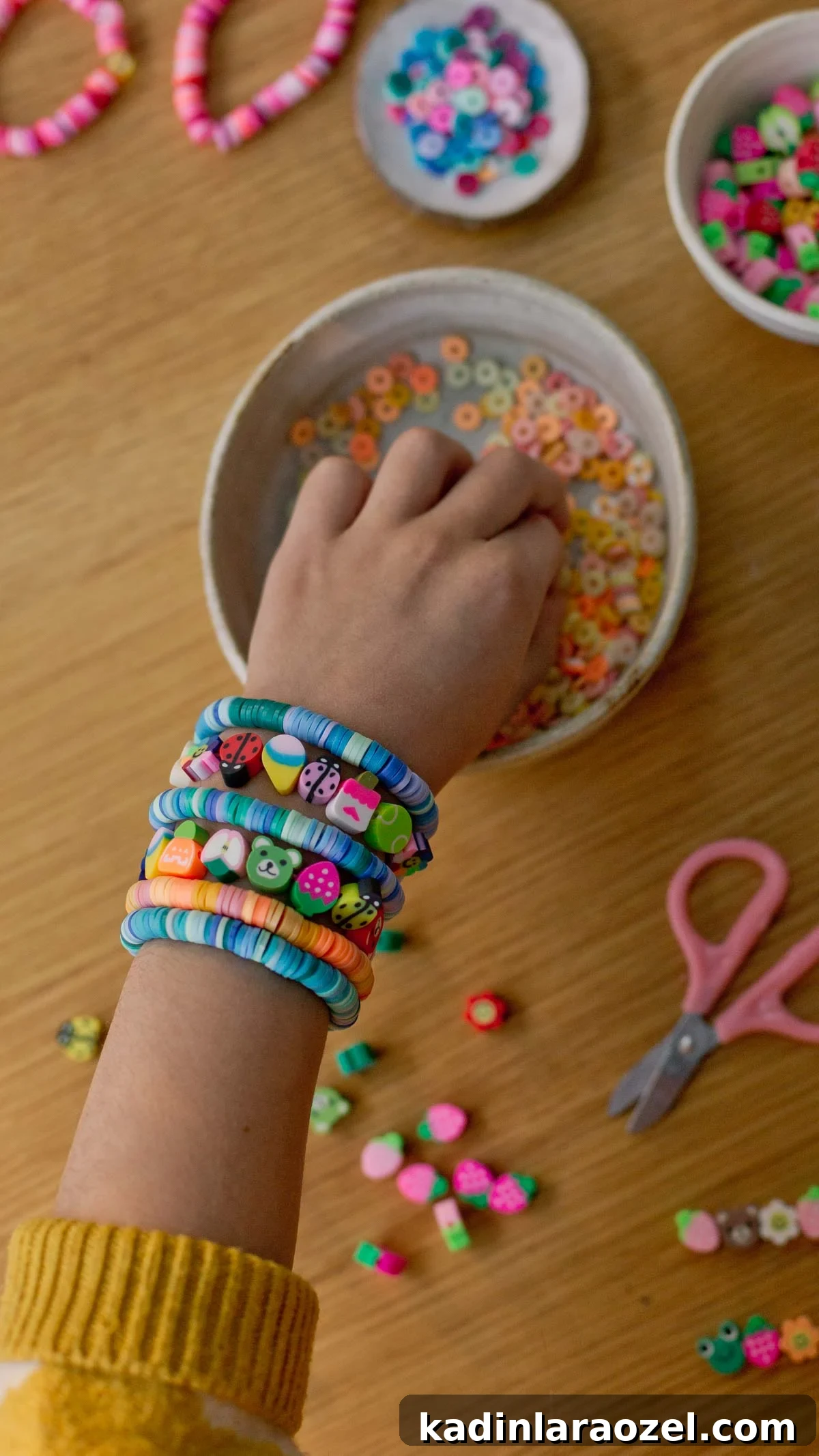 Creative Clay Bead Bracelet Designs and Styling Ideas 4 child's hand reaching into a bowl of clay beads, who is wearing a lot of clay bead bracelets on his wrist