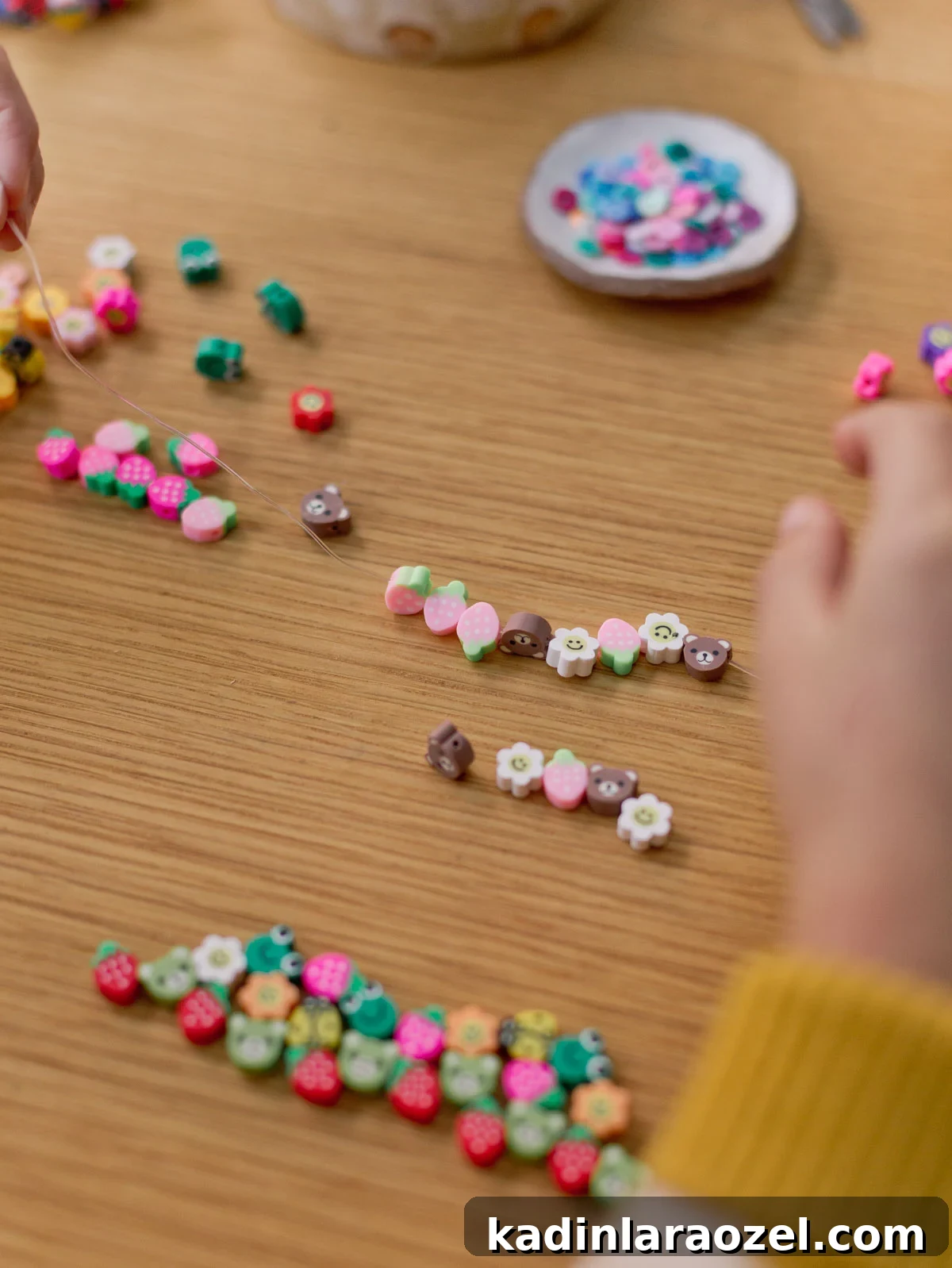 Creative Clay Bead Bracelet Designs and Styling Ideas 6 child putting together a colorful beaded bracelet by stringing clay beads onto a clear string