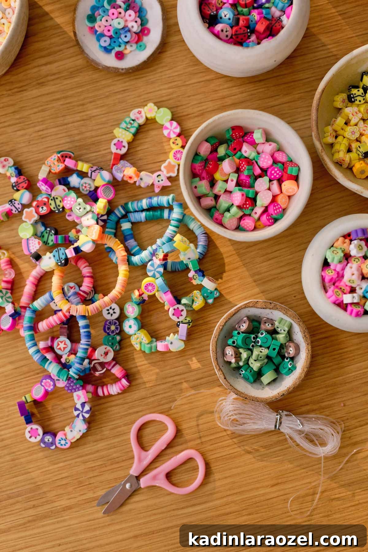 Creative Clay Bead Bracelet Designs and Styling Ideas 7 bowls of beads and clay bead bracelets laying out on wood surface with scissors and other supplies