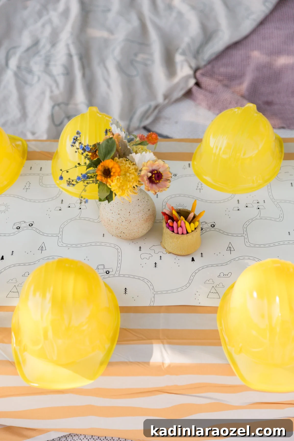 Construction and Car-Themed Birthday Party Ideas for Kids 8 yellow construction hats lined up on a table with an orange and white striped tablecloth