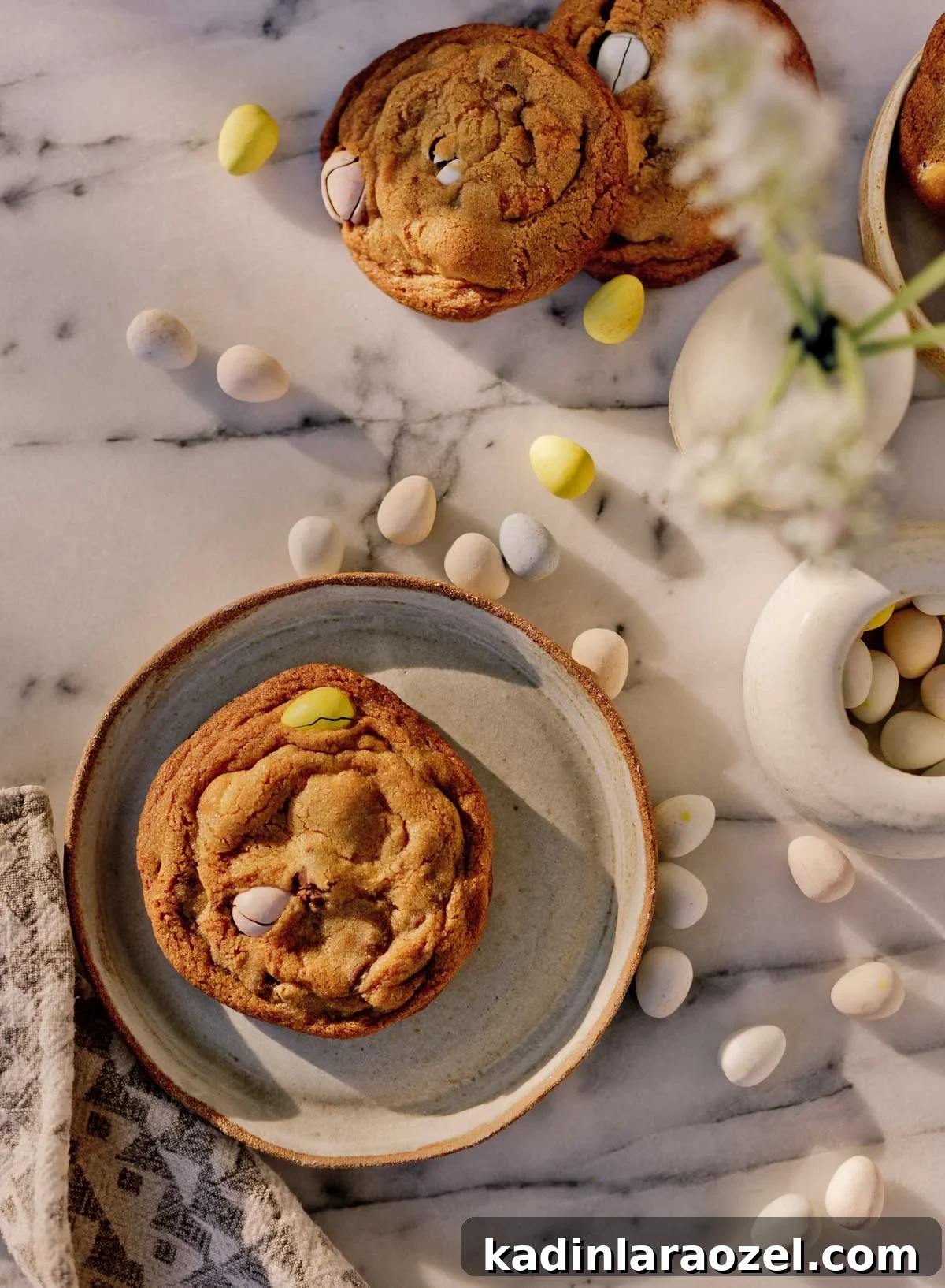 Cadbury Chocolate Chip Cookie Recipe — Chewy, Chocolatey Treats 2 large easter cookie with cadbury chocolate eggs, sitting on marble countertop