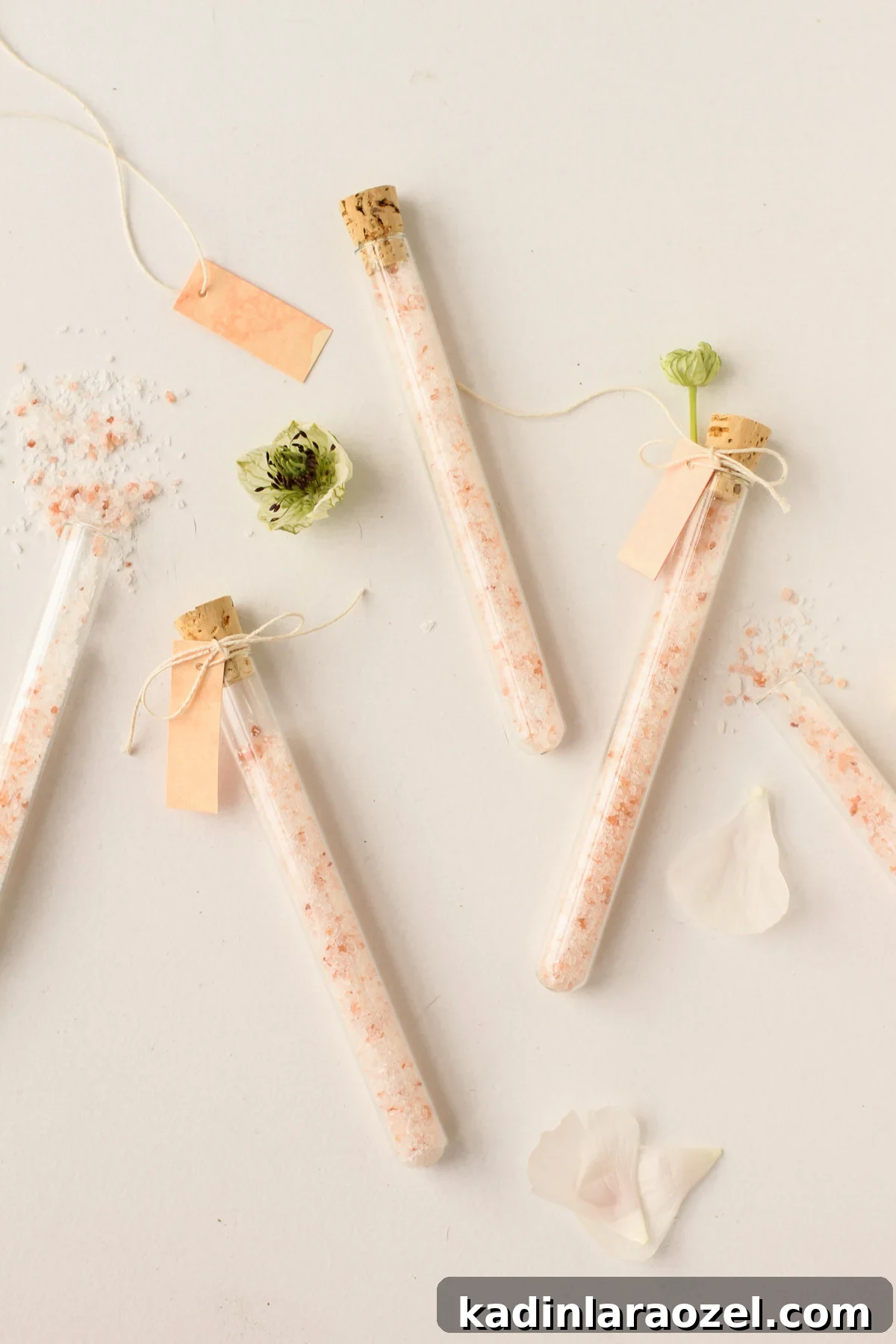 DIY Bath Salts Recipe for Memorable Wedding Favors 11 diy bath salts spilling out of clear glass vials on a white counter with flowers