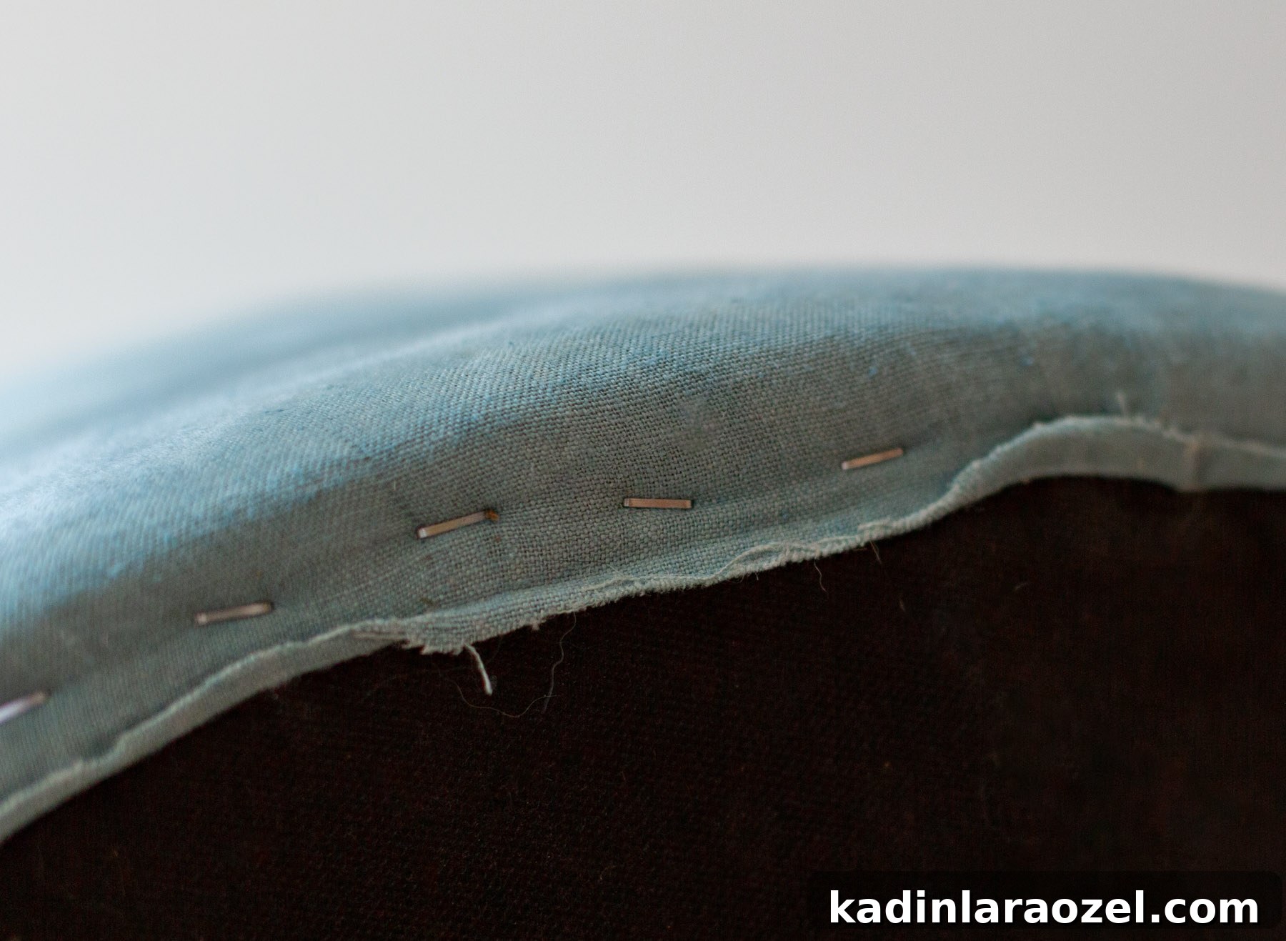 closeup of blue fabric with staples in a round shape