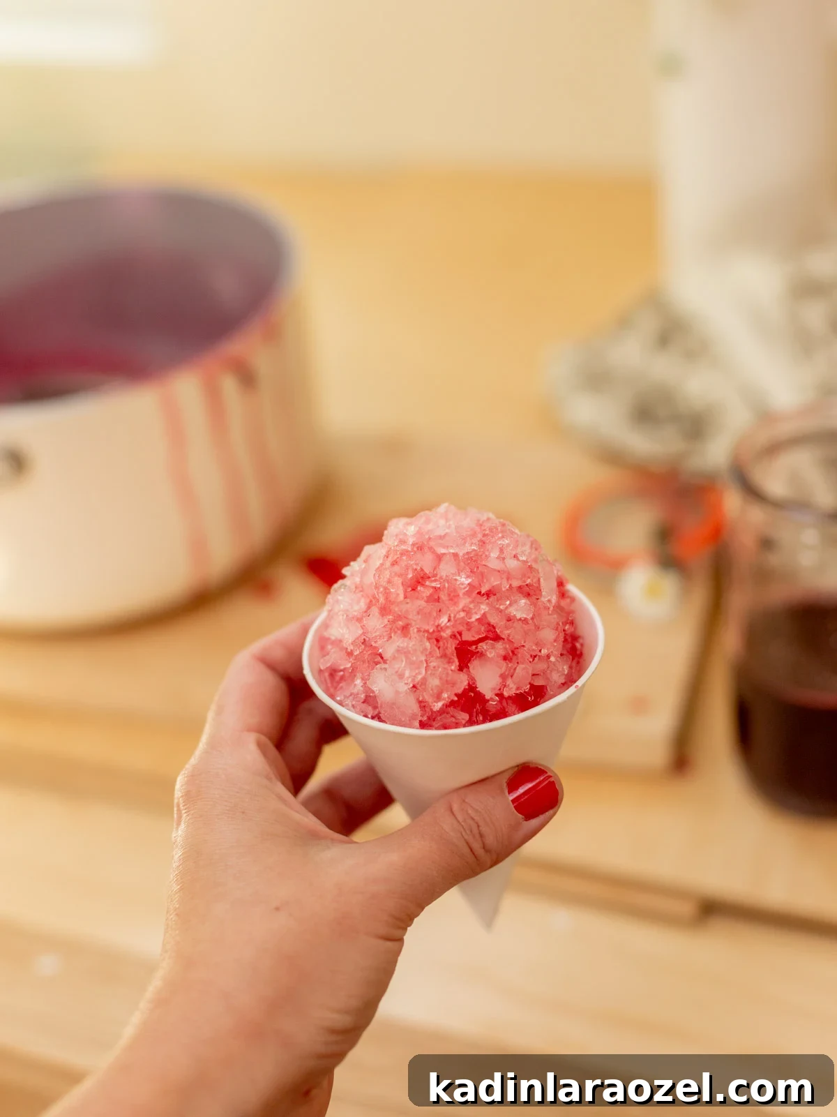 Three-Ingredient Blackberry Syrup Recipe for Pancakes and Desserts 2 woman holding pink snow cone in hand inside a wood kitchen
