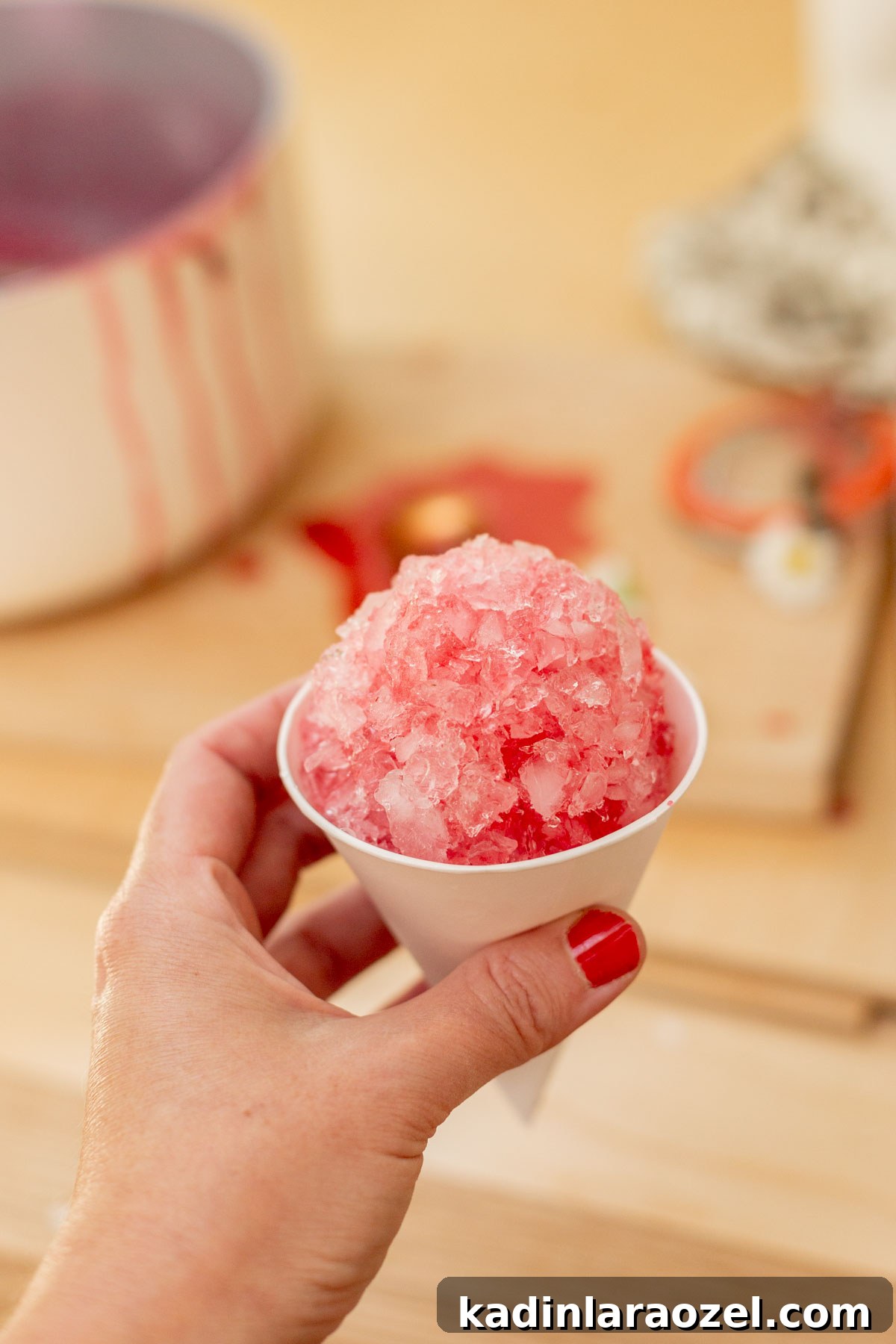 Three-Ingredient Blackberry Syrup Recipe for Pancakes and Desserts 10 woman's hand holding pink snow cone in light-filled kitchen