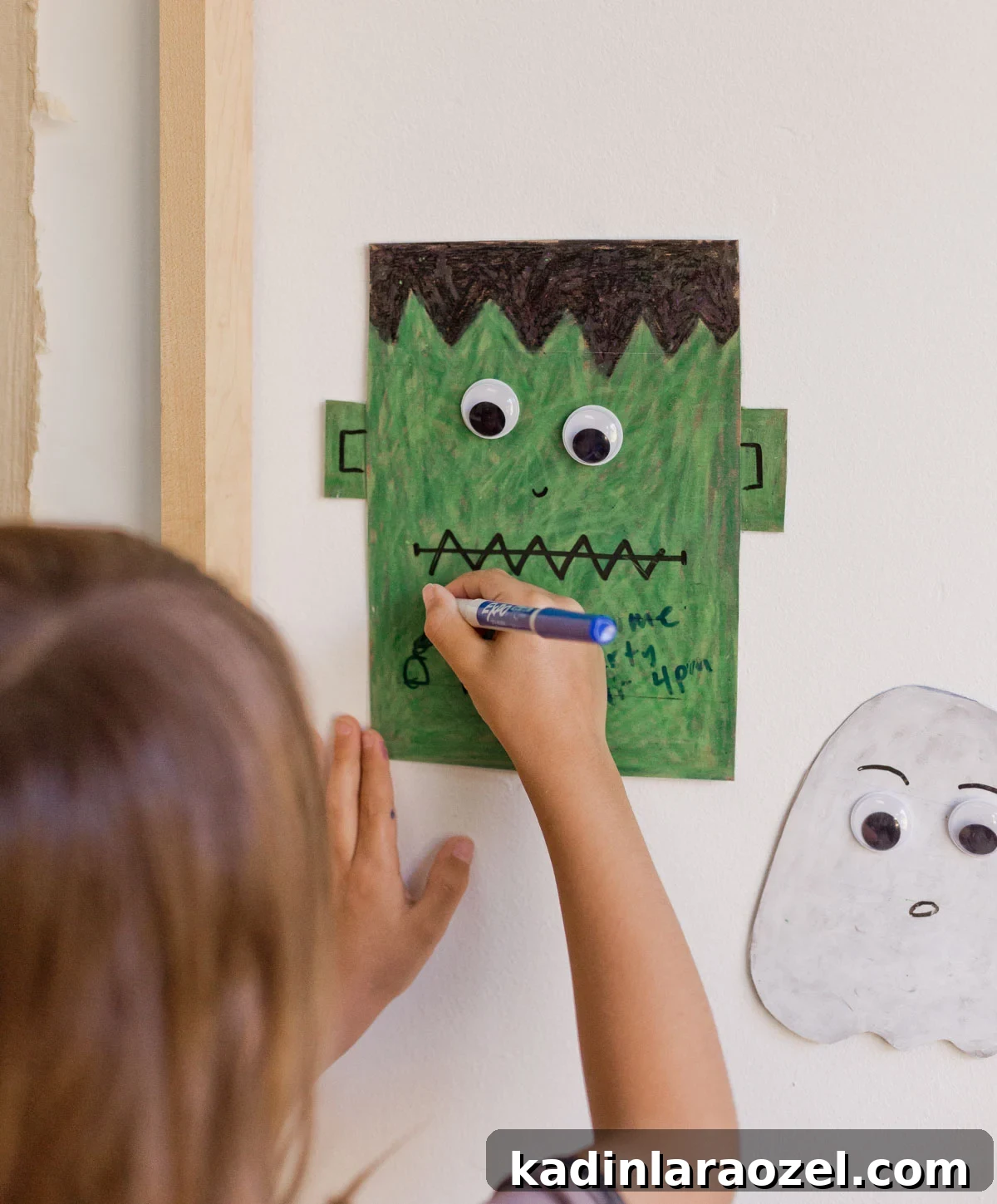 young child drawing on a halloween dry erase board that is on the wall