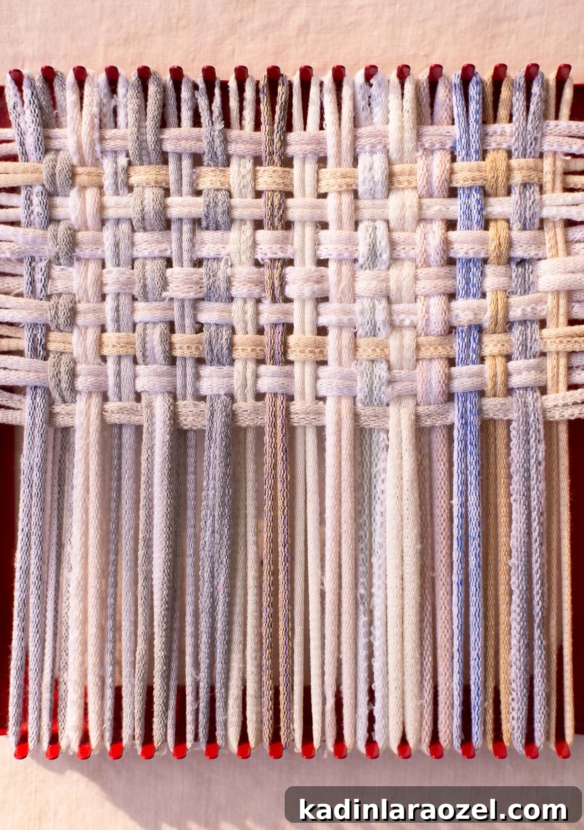 halfway done weaving on a potholder loom with neutral color loops