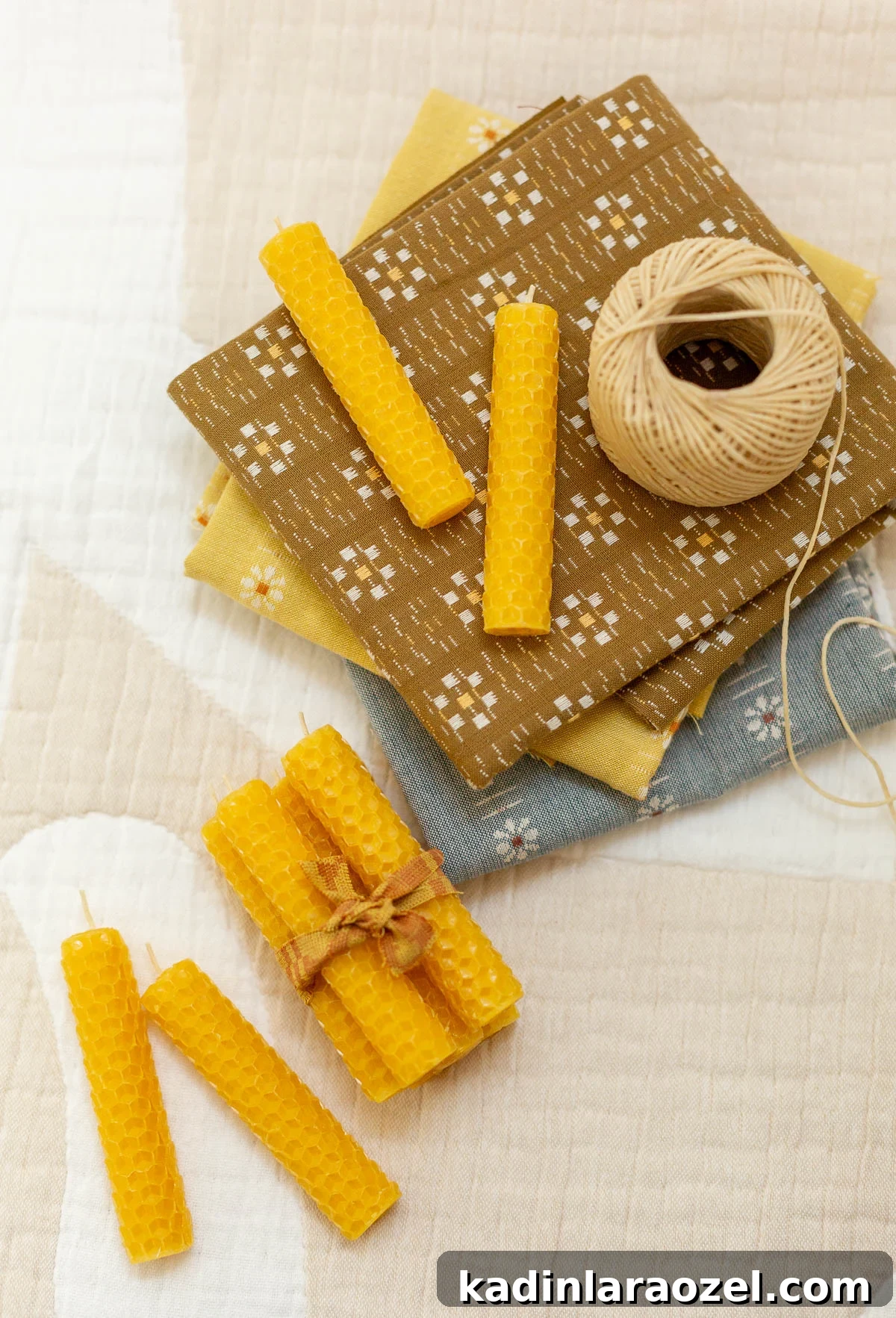 Make Rolled Beeswax Candles: Step-by-Step Guide for Beginners 2 rolled beeswax candles on fabric scraps in a crafting room