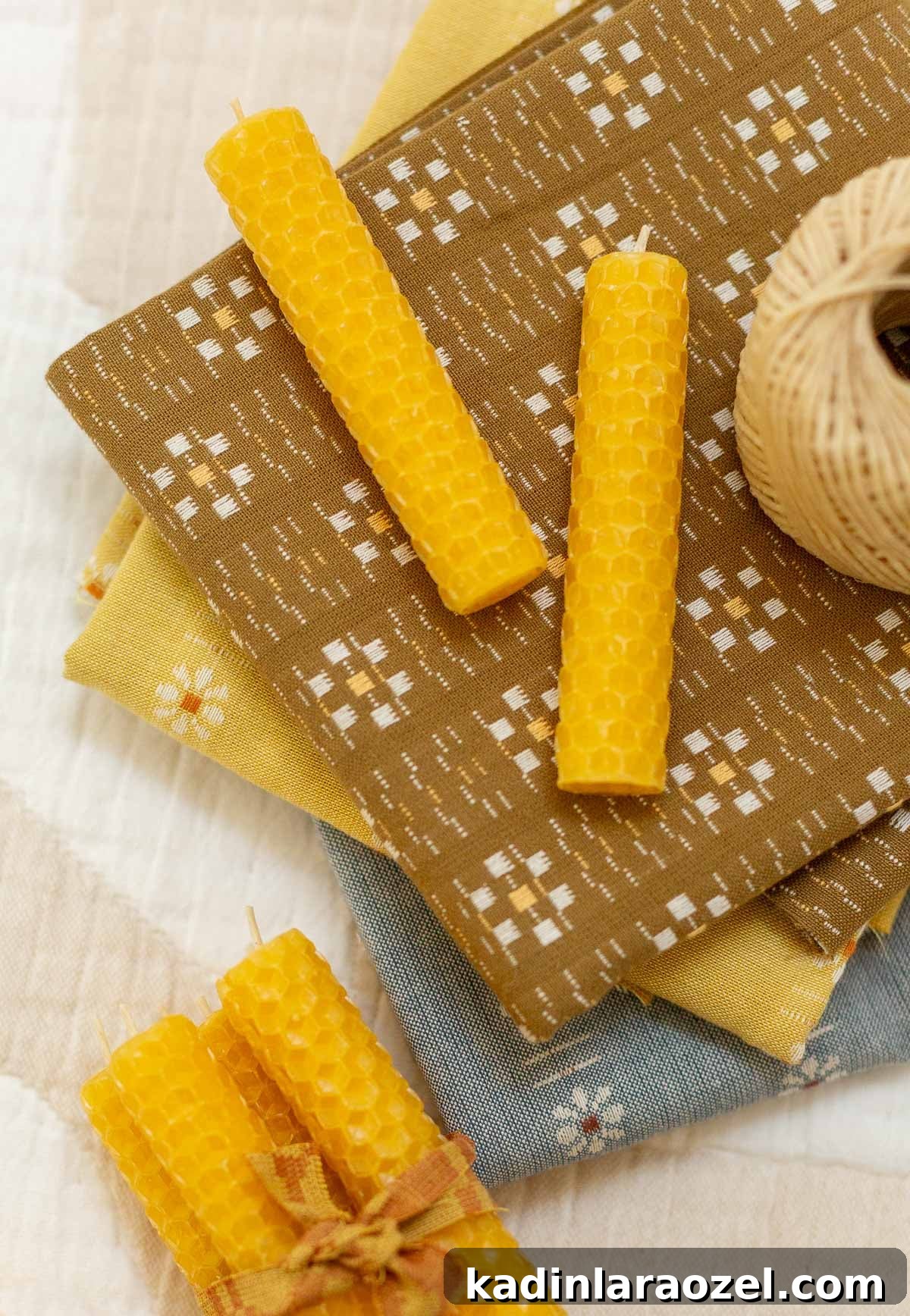 Make Rolled Beeswax Candles: Step-by-Step Guide for Beginners 10 yellow beeswax rolled candles on stack of neutral pattern fabrics
