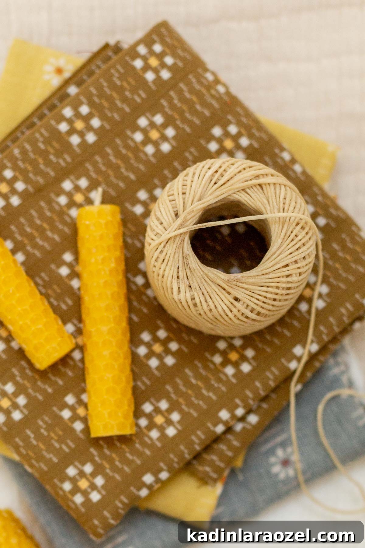 Make Rolled Beeswax Candles: Step-by-Step Guide for Beginners 9 closeup on ball of waxed wick with rolled beeswax candles on stack of vintage fabric