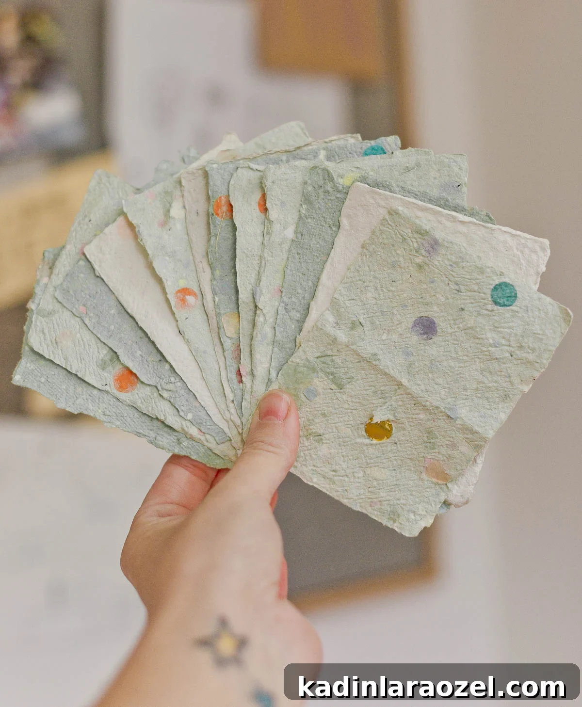 person holding stack of homemade paper in hand, like a deck of cards