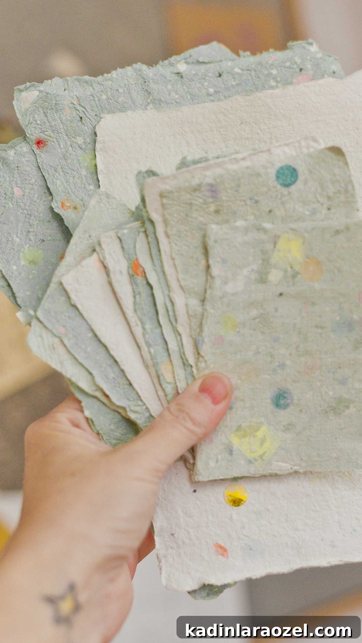 holding up pastel homemade paper stack