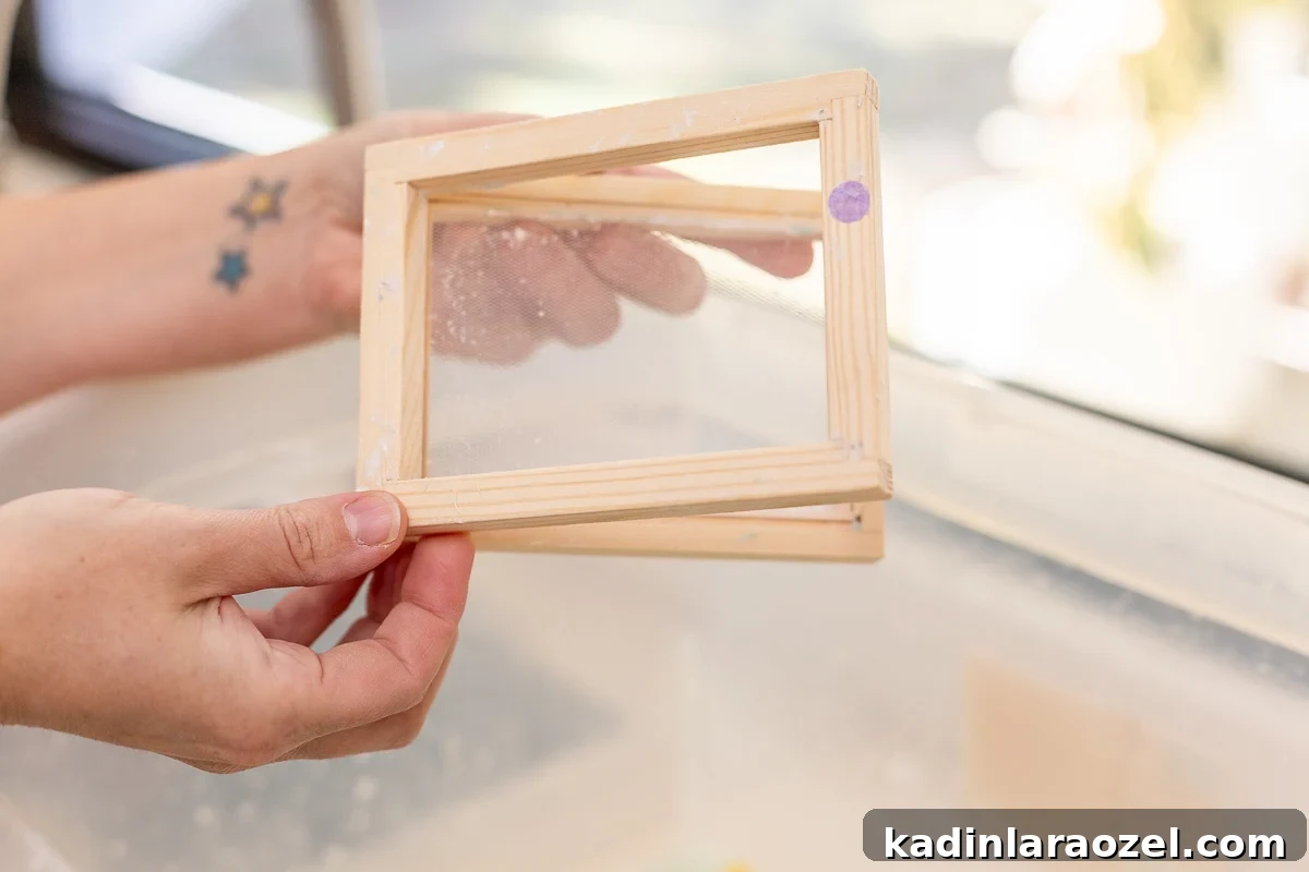 holding a small paper mould screen above a container filled with paper slurry for paper making 