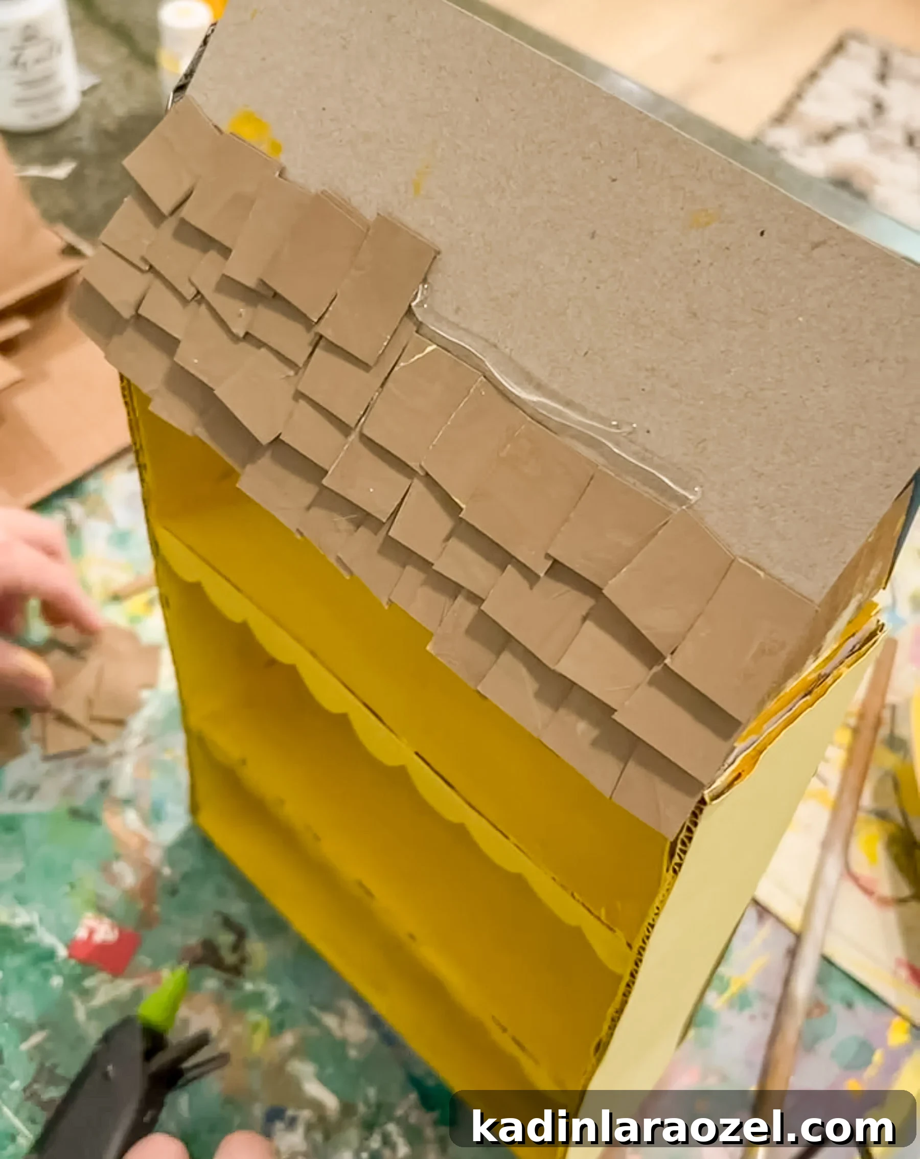 DIY Cardboard Dollhouse Made from a Cereal Box 6 glueing cardboard shingles to a cereal box to make a roof for a dollhouse