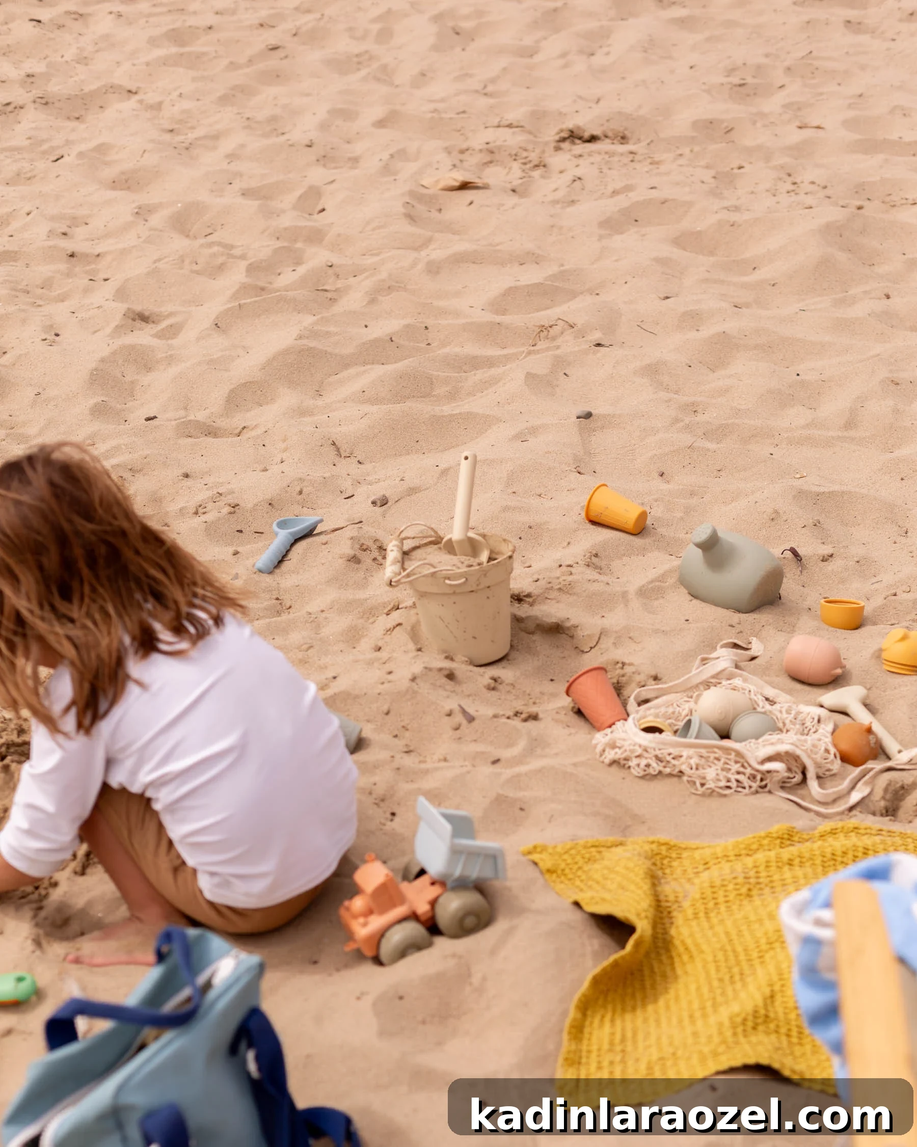 17 Fun Beach Activities for Kids and Families 4 child playing in sand at beach with colorful toys