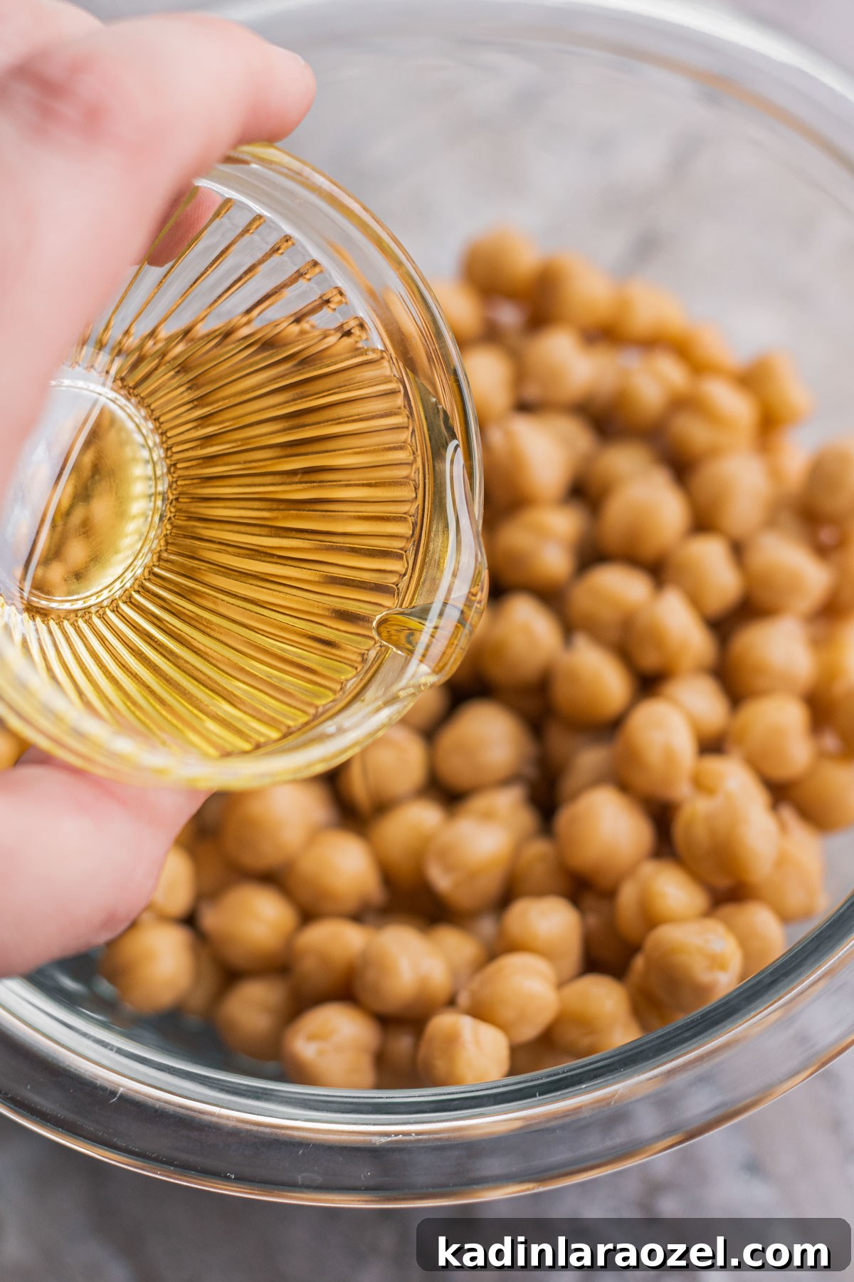 Crispy Roasted Chickpeas Recipe for Snack or Salad Topping 4 pouring small amount of olive oil over a bowl of chickpeas