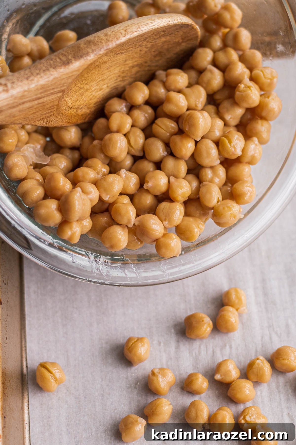 Crispy Roasted Chickpeas Recipe for Snack or Salad Topping 5 pouring chickpeas from a bowl onto a baking sheet to cook up and make crispy