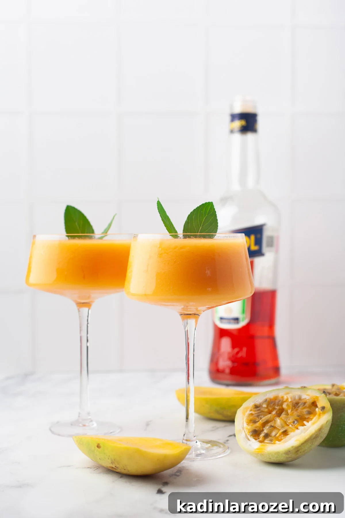 two frozen cocktails in vibrant colors, sitting on kitchen counter