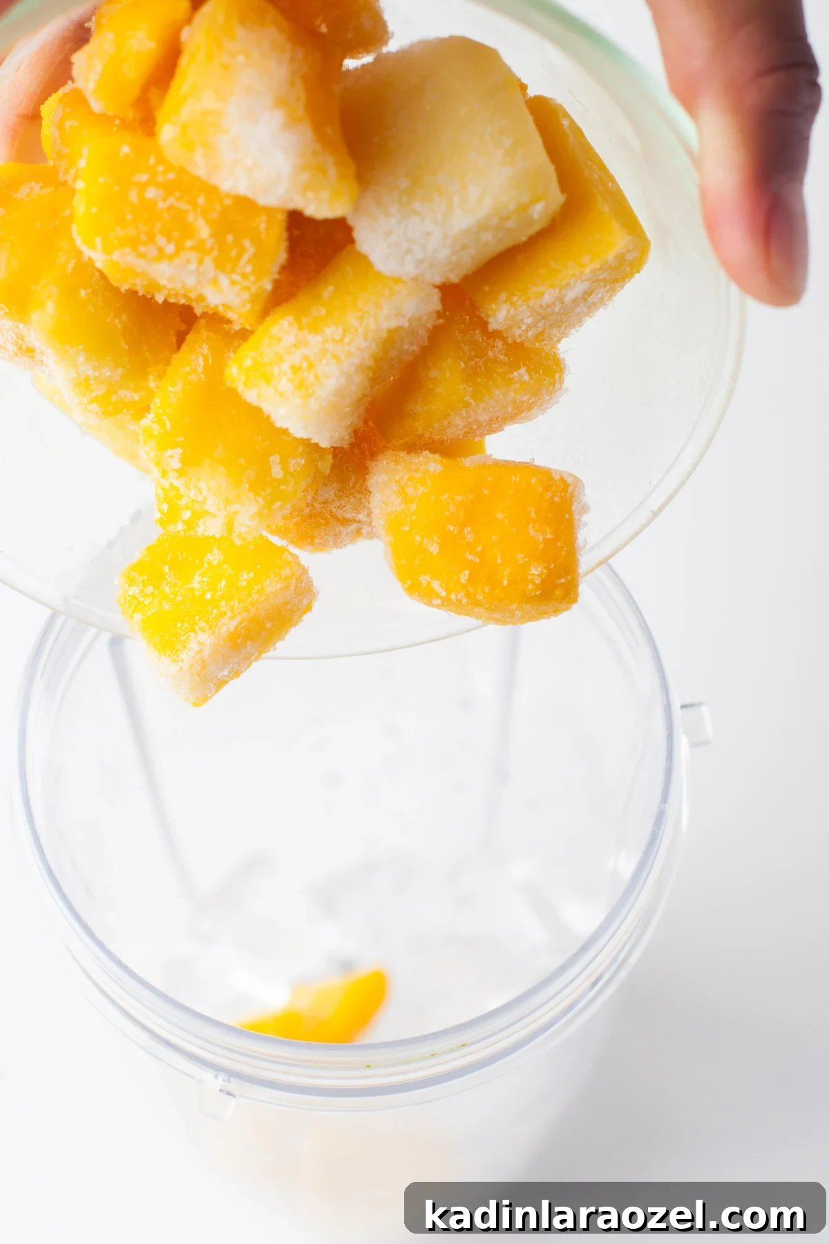 pouring frozen mango into a blender