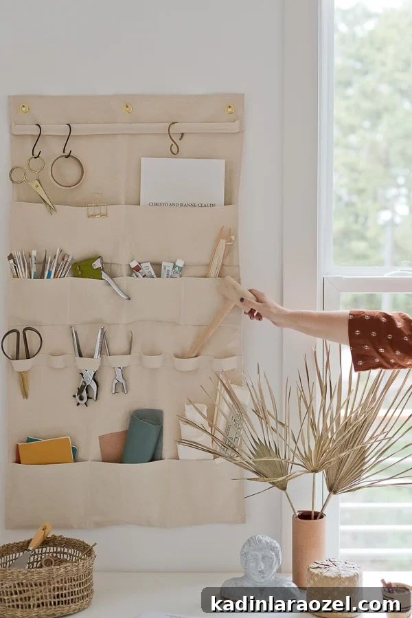 woman's hand removing art supplies from canvas wall organizer in a creative office workspace