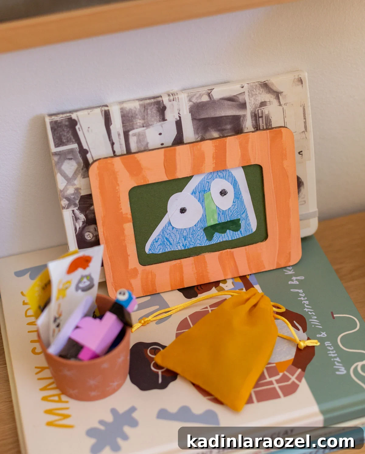 framed kids monster art made from junk mail, sitting on a stack of books in cool kids bedroom