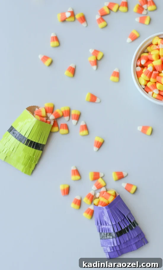 fringe party favor bags in green and purple with candy corn filling each one