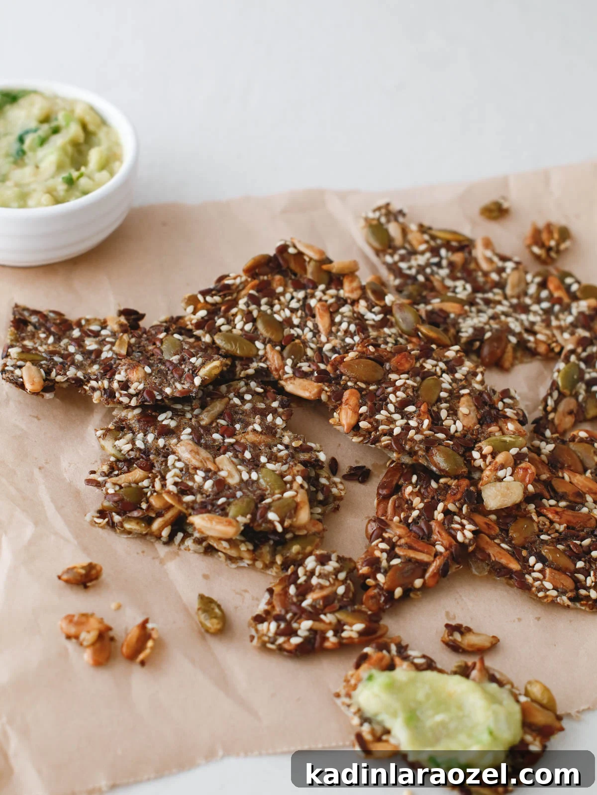 Crispy Seed Crackers Recipe: Homemade Savory Snack 11 homemade crackers with seeds in them, on a kitchen countertop with dips