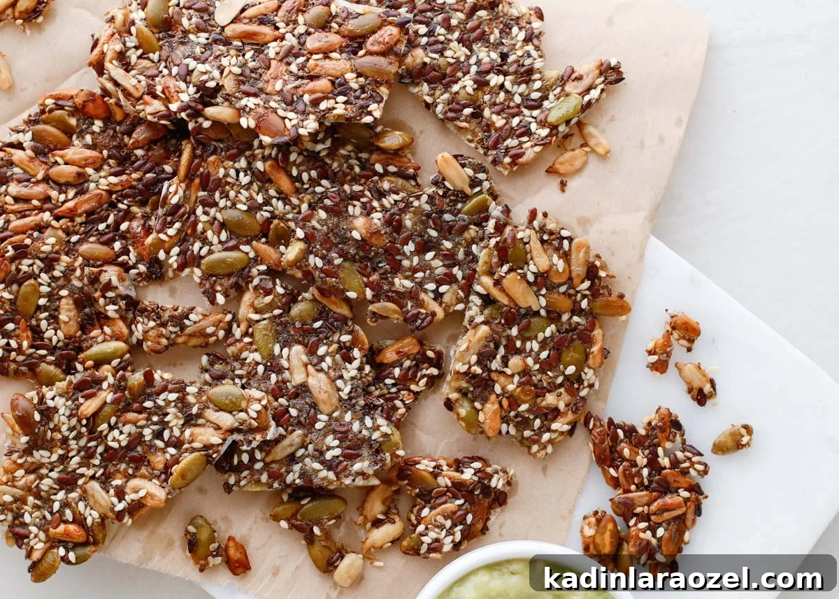 Crispy Seed Crackers Recipe: Homemade Savory Snack 3 brown seed crackers in small pieces with green spread in small bowl nearby