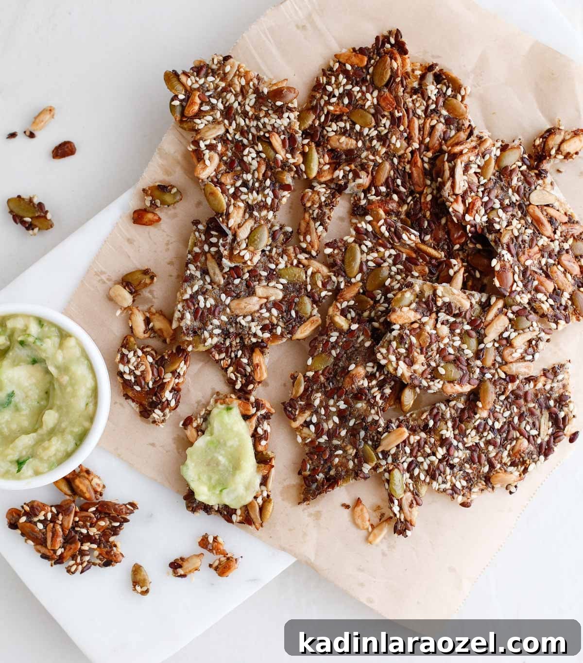 Crispy Seed Crackers Recipe: Homemade Savory Snack 9 seed crackers on a marble board with avocado spread