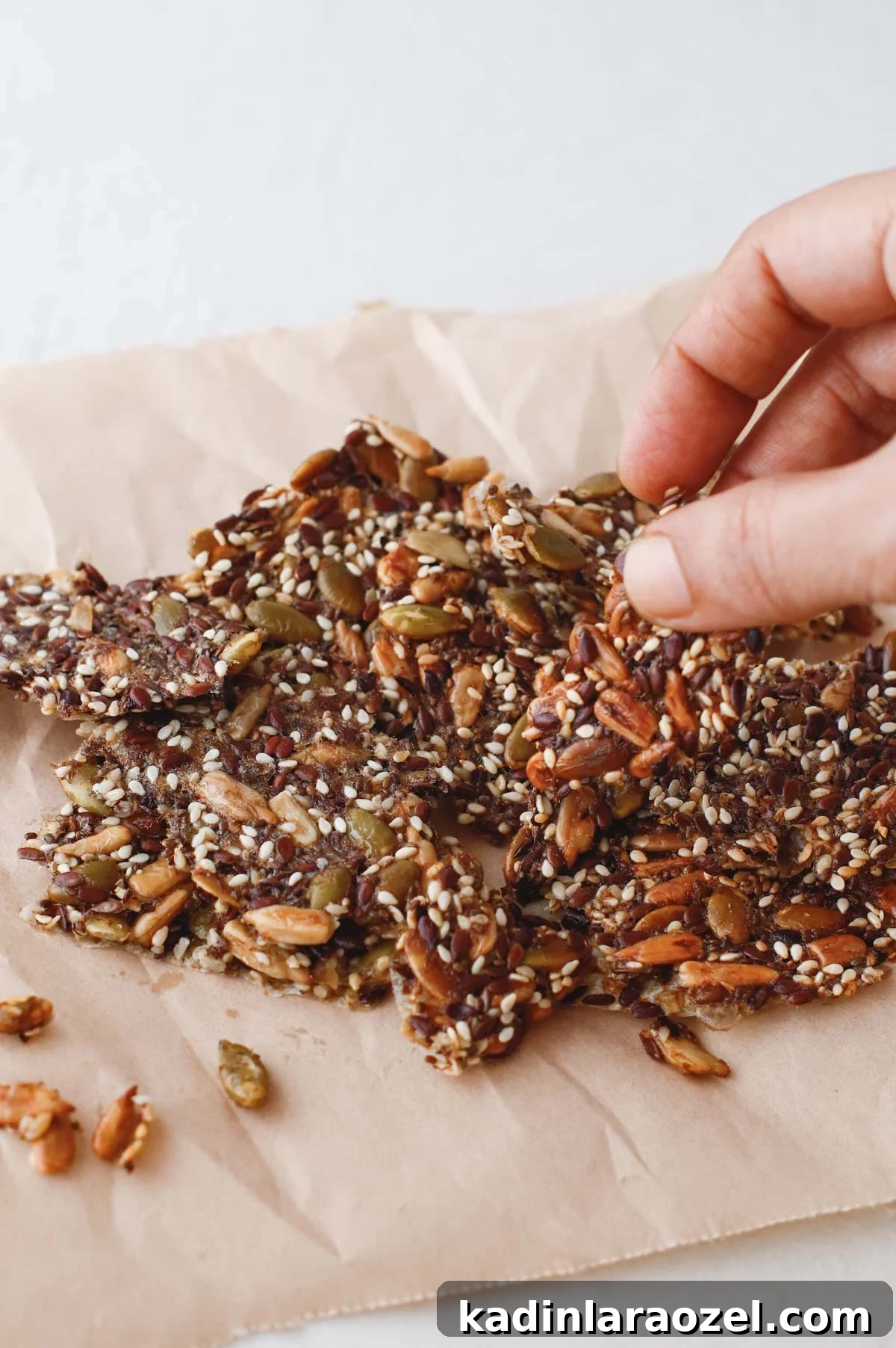 Crispy Seed Crackers Recipe: Homemade Savory Snack 10 person grabbing small homemade seed cracker from pile on a cracker board