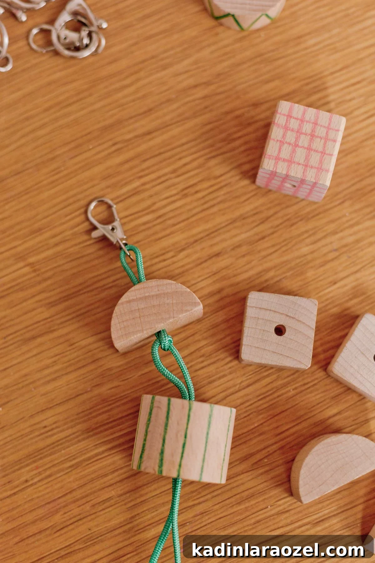 stringing wood blocks onto green cording with lobster clasp
