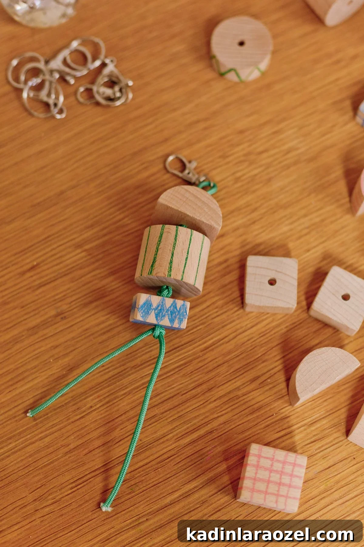 chunky wood keychain with green cording and simple patterns drawn onto blocks