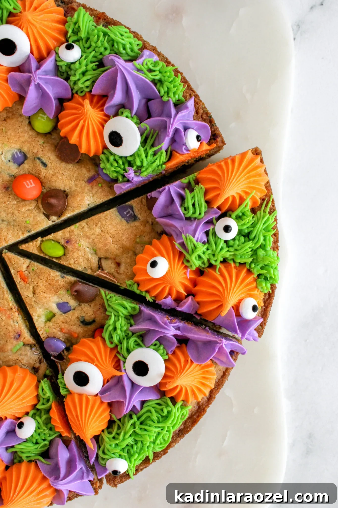 27 Spooky Halloween Desserts to Delight Your Guests 8 closeup of large cookie cake with colorful frosting details and halloween inspired googly eyes candy