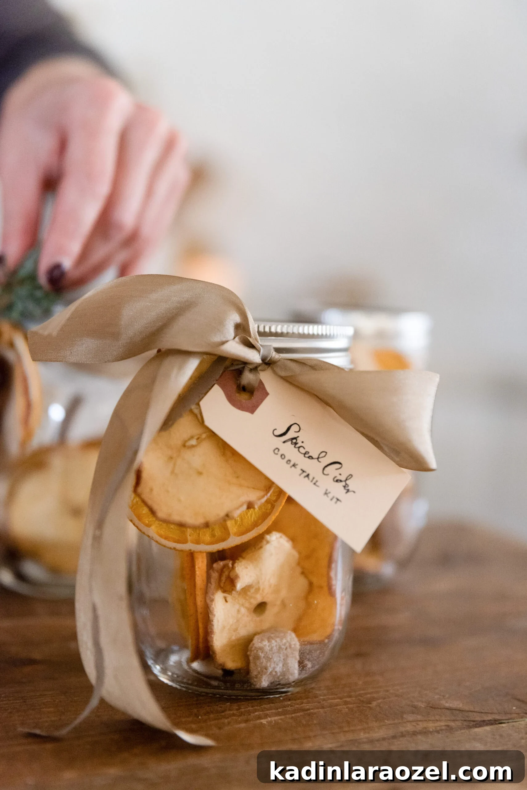 spiced cider cocktail jar gift, with a woman adding a silk ribbon