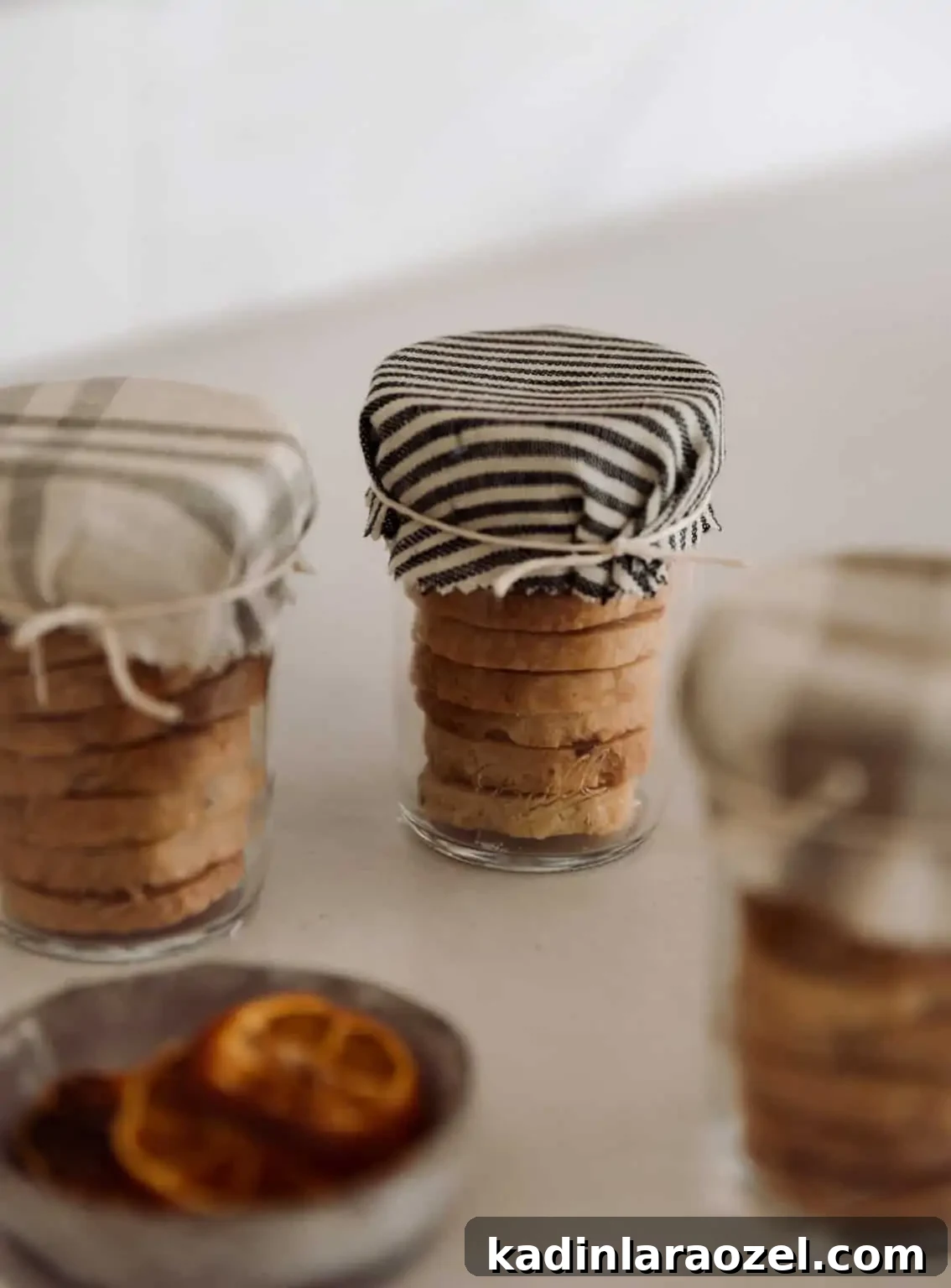 small stacked cookies in glass jars with fabric over the top and string