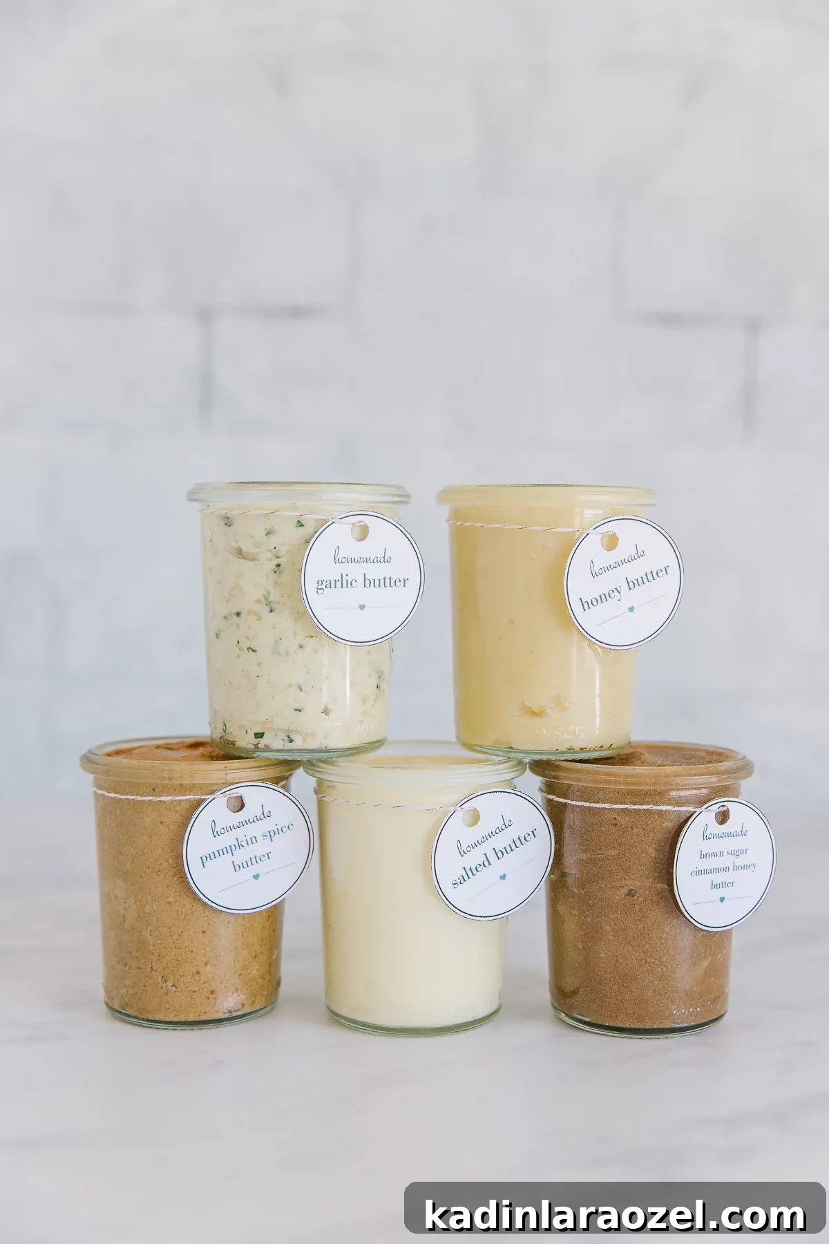 five glass jars stacked on top of each other, each with a different flavor of butter in each one