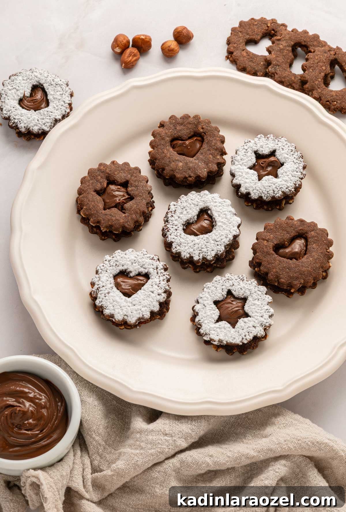 Decadent Chocolate Hazelnut Cookie Recipe 13 linzer cookies on a beige plate, with nutella dip nearby