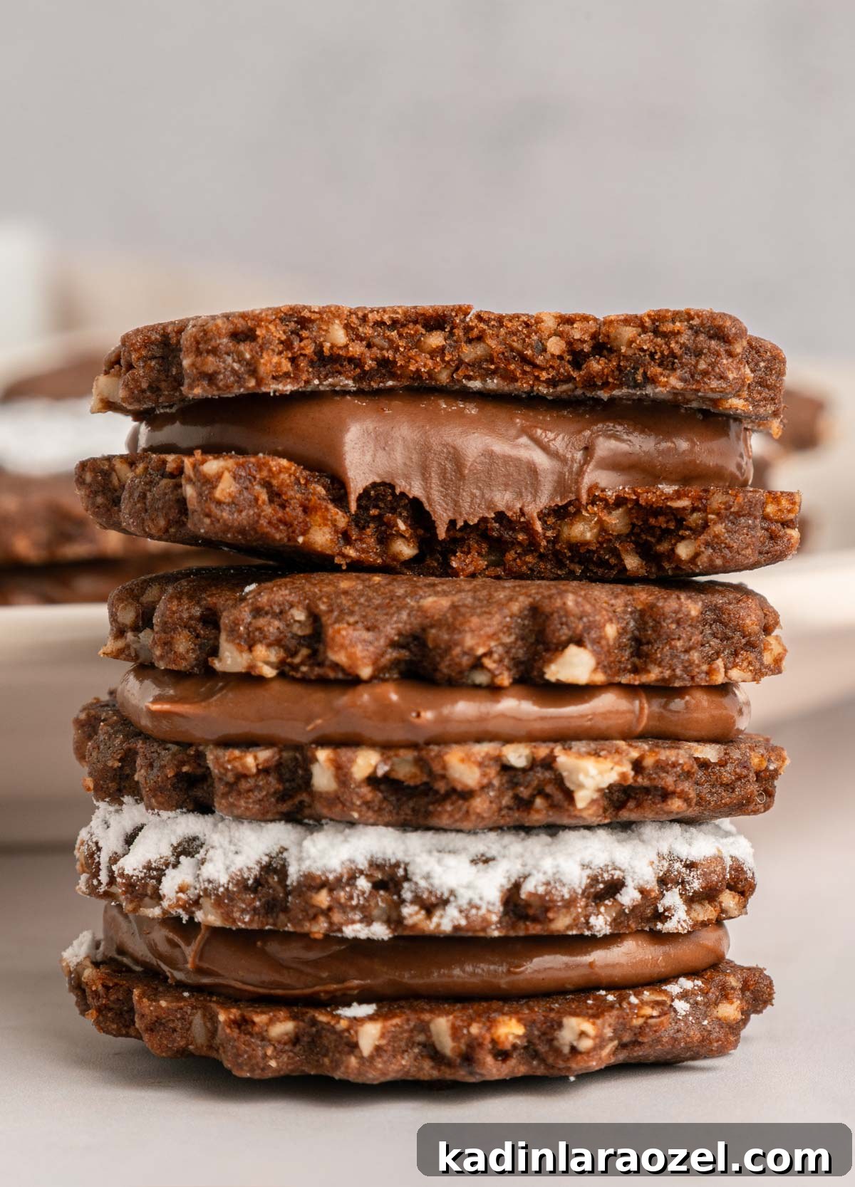 Decadent Chocolate Hazelnut Cookie Recipe 18 closeup of chocolate linzer cookies with nutella coming out of the sides of each sandwich