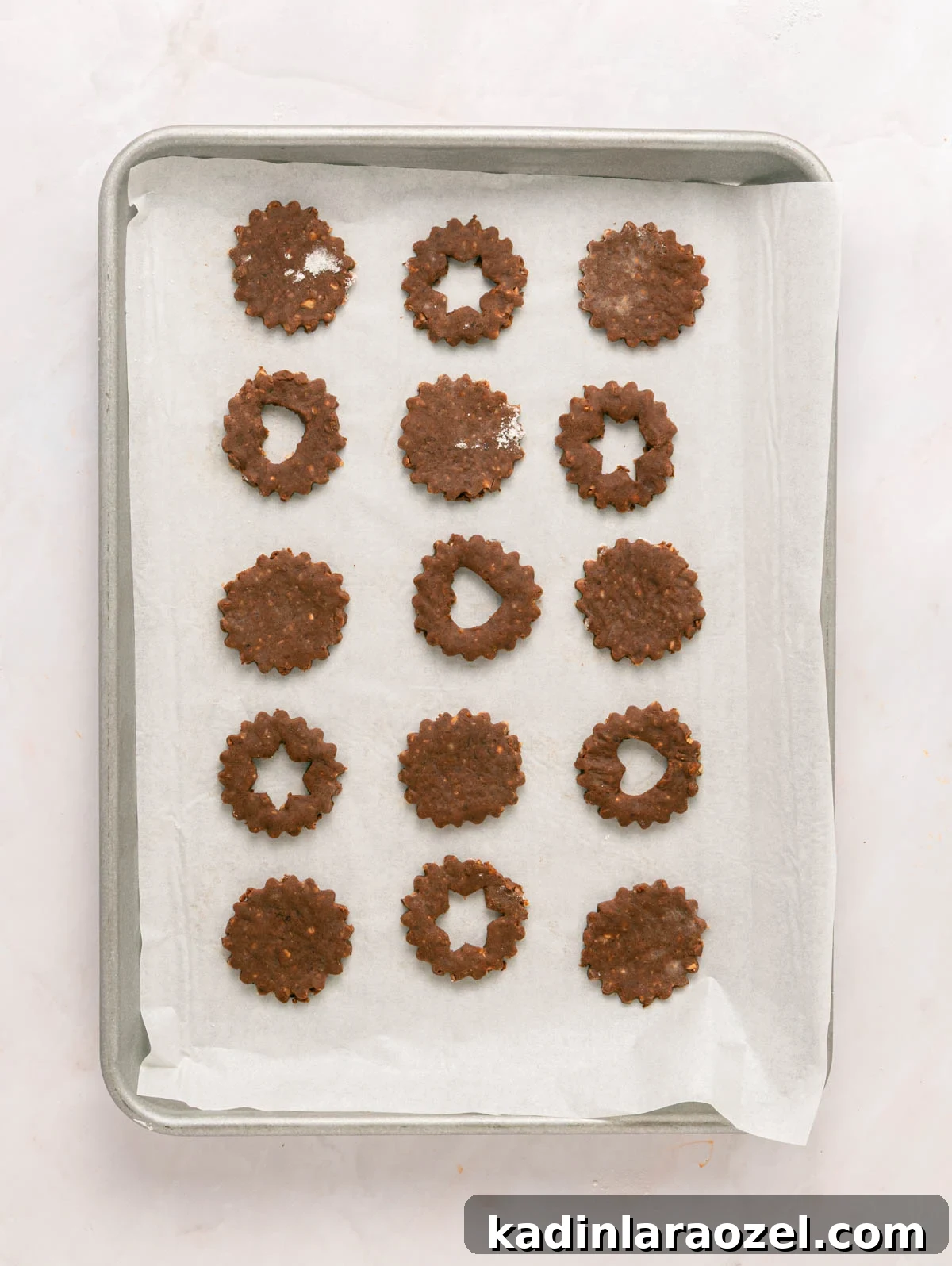 Decadent Chocolate Hazelnut Cookie Recipe 8 chocolate linzer cookies on a baking sheet, lined up and ready to bake