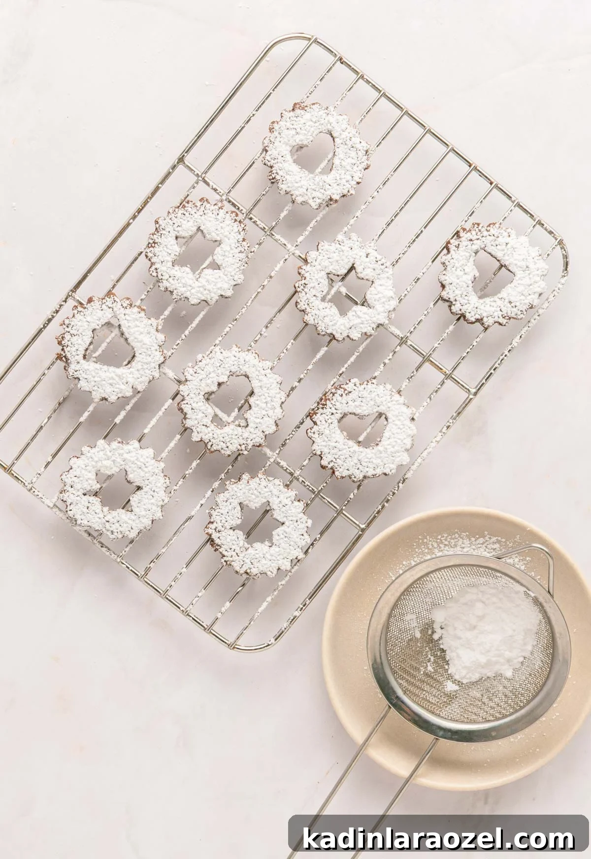 Decadent Chocolate Hazelnut Cookie Recipe 9 linzer cookies being topped with powdered sugar on a cooling rack