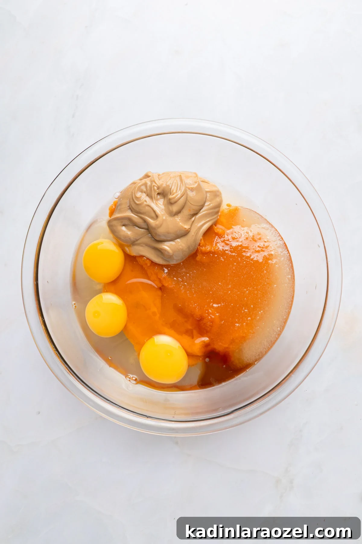 ingredients in a bowl for brownies, including eggs, peanut butter, sweet potato, and more
