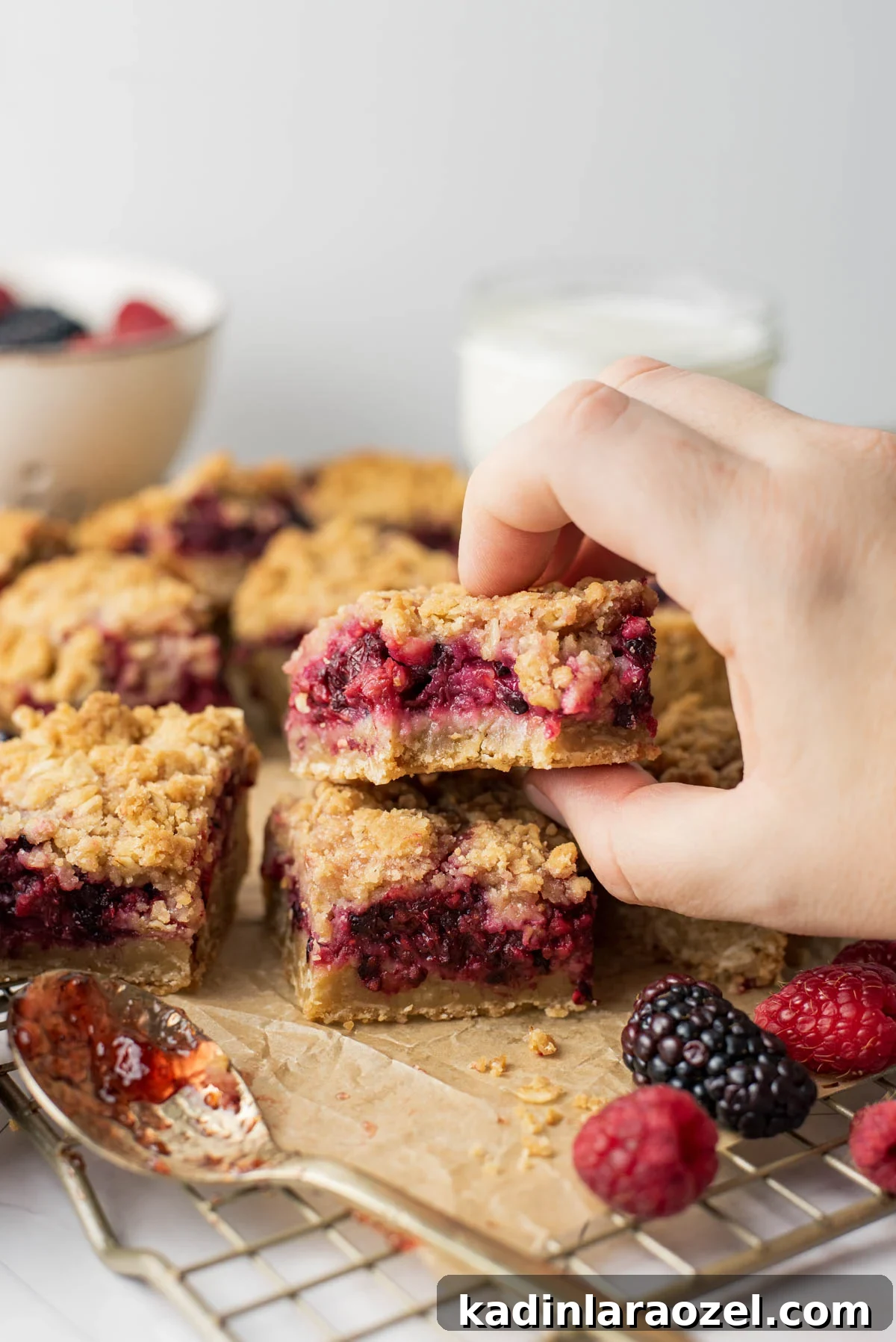 Berry Oat Shortbread Bars — Tender Crust with Fresh Berries 13 woman's hand picking up a small dessert bar