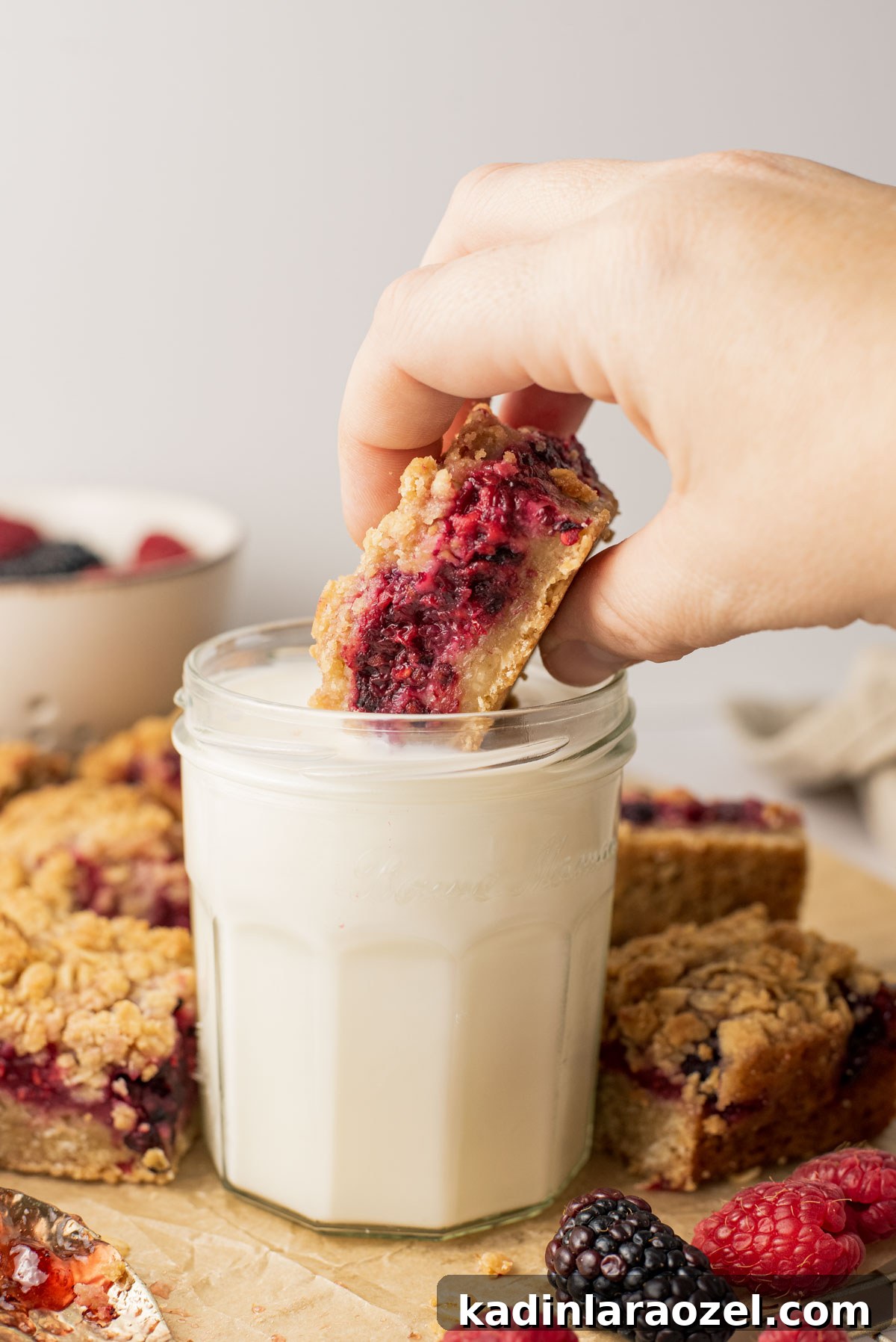 Berry Oat Shortbread Bars — Tender Crust with Fresh Berries 9 dunking shortbread bars into short glass of milk, with hands
