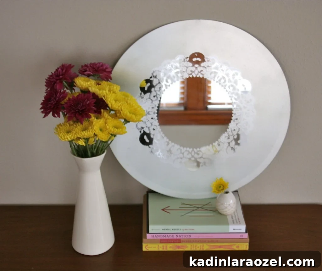 Frosted glass mirror with a doily design pattern, sitting on a walnut dresser.