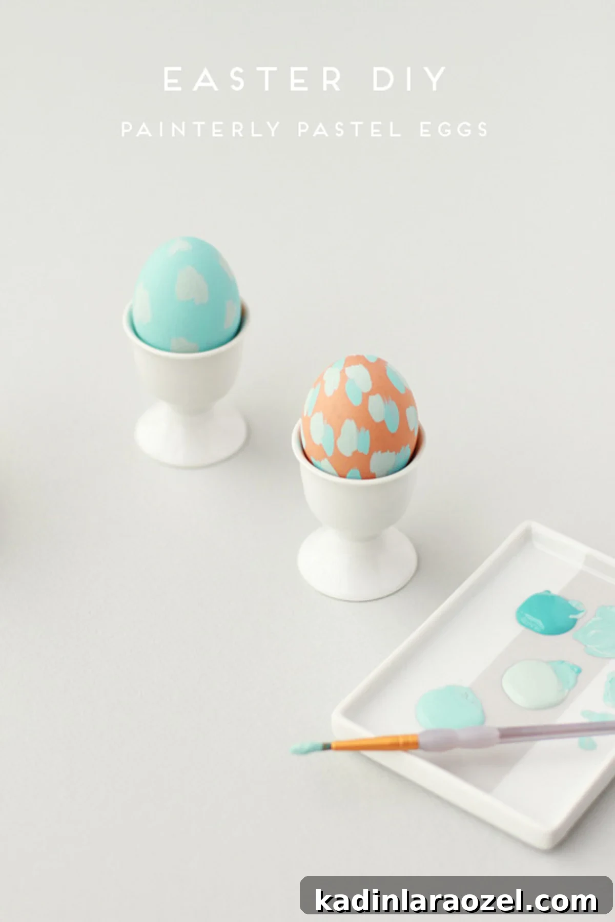 pastel painted easter eggs in white egg cups with palette filled with blue paint nearby