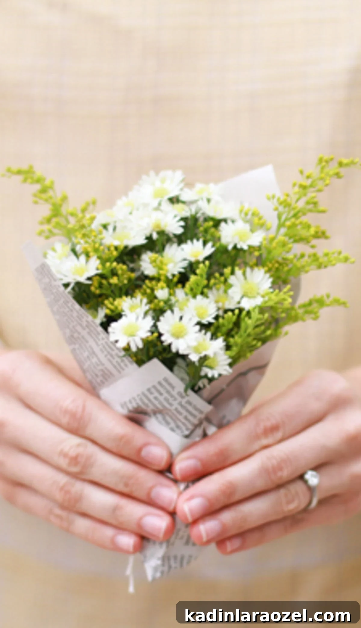 woman wearing wedding ring holding small bouquet of flowers wrapped in newspaper