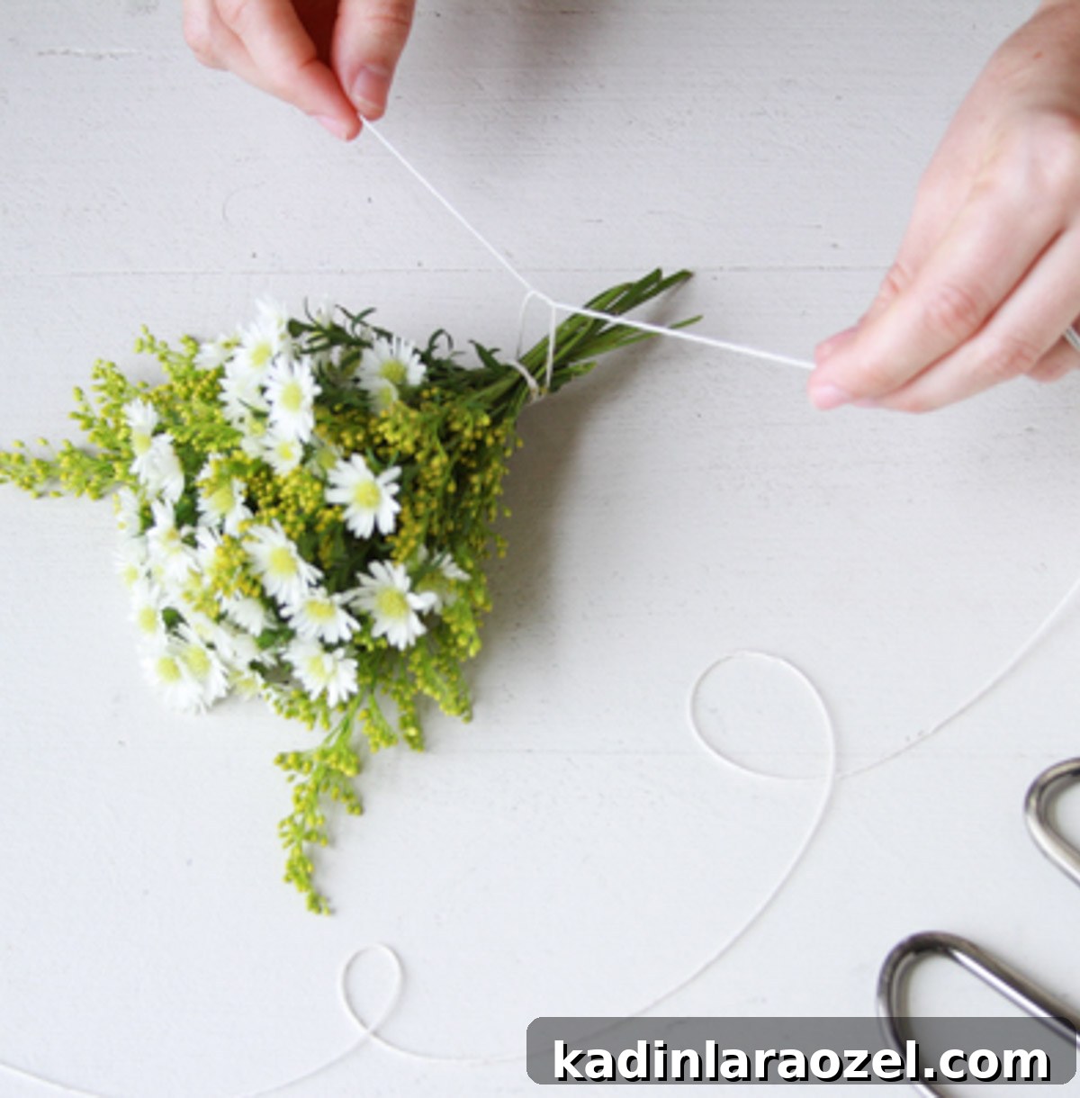 woman tying a string to the bottom of a small bouquet